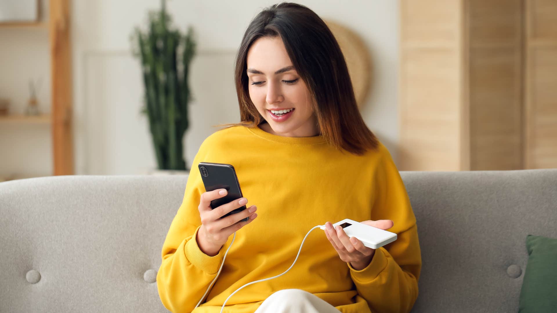 woman using a power bank in her living room to charge her phone