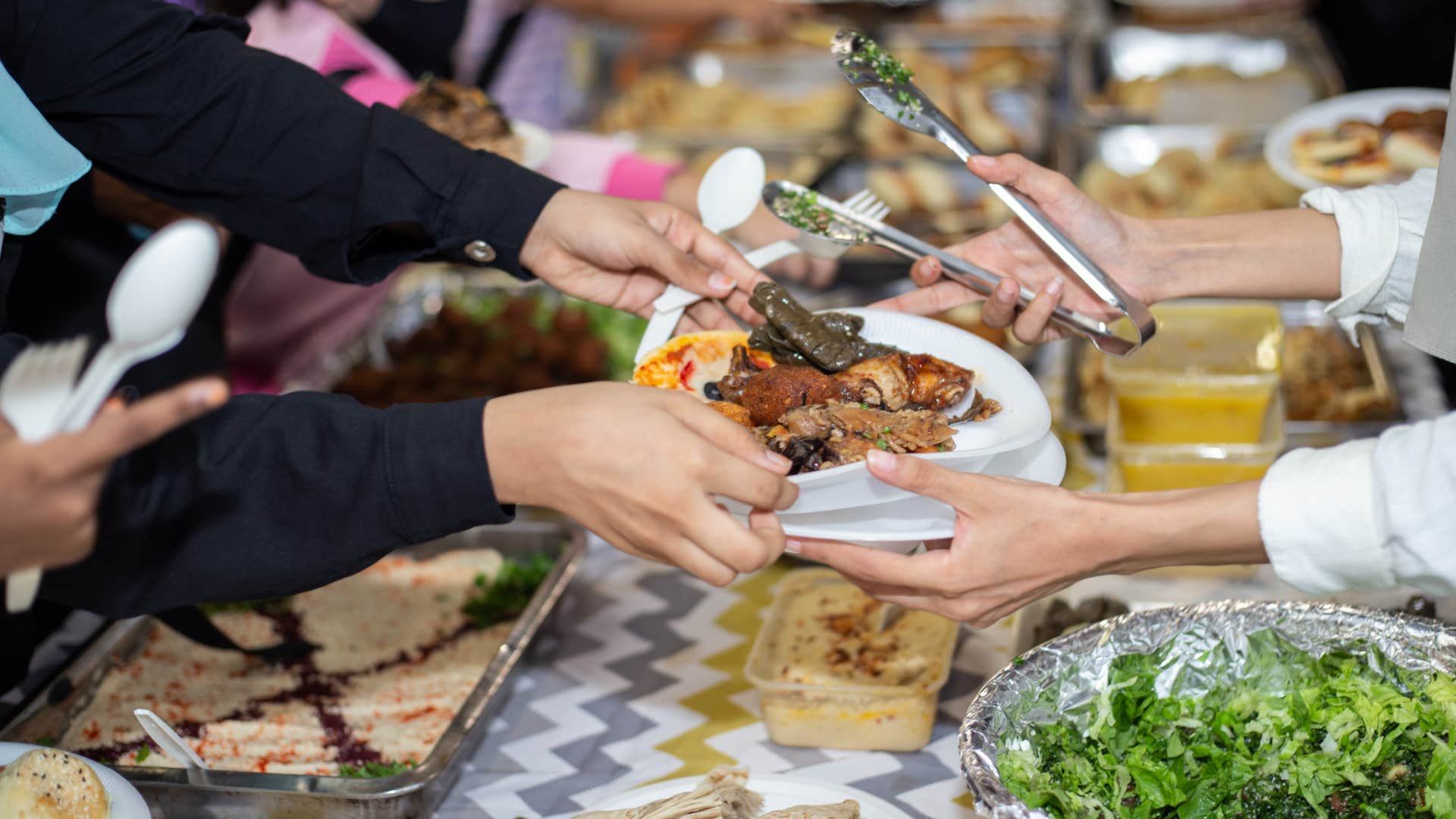 group of people using disposable cutlery and paper plates at dinner