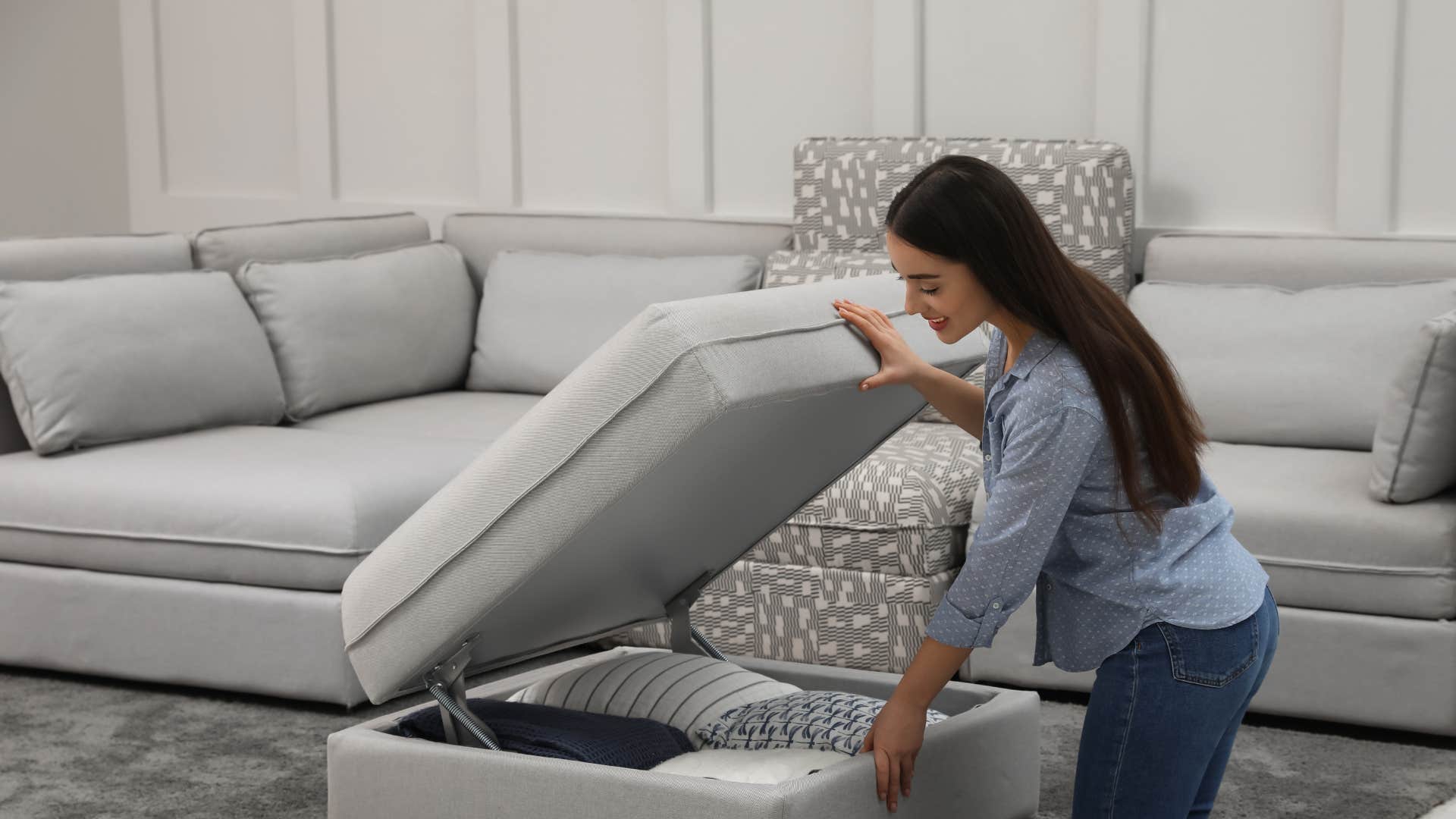 woman using a storage ottoman for her couch pillows