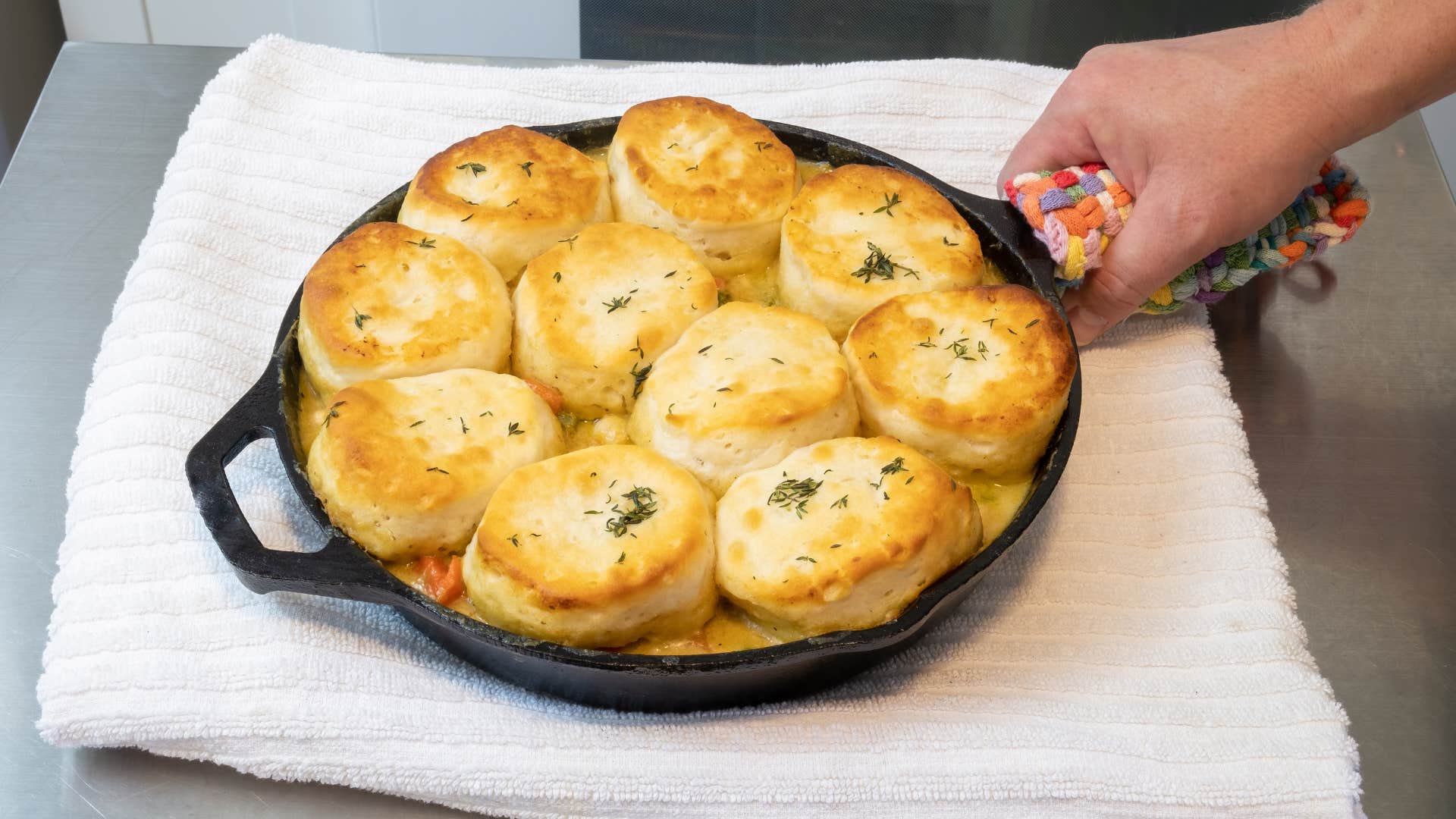 person holding a cast iron skillet with biscuits 