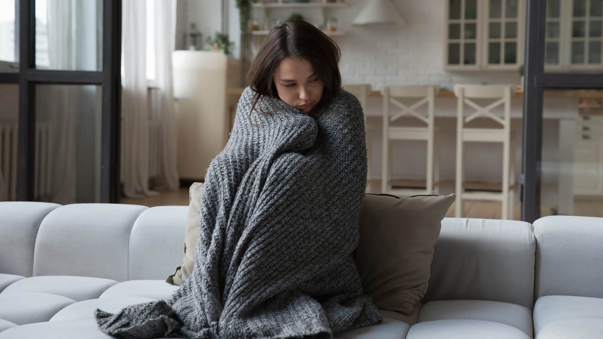 woman with a gray homemade quilt lying around wrapping it around herself