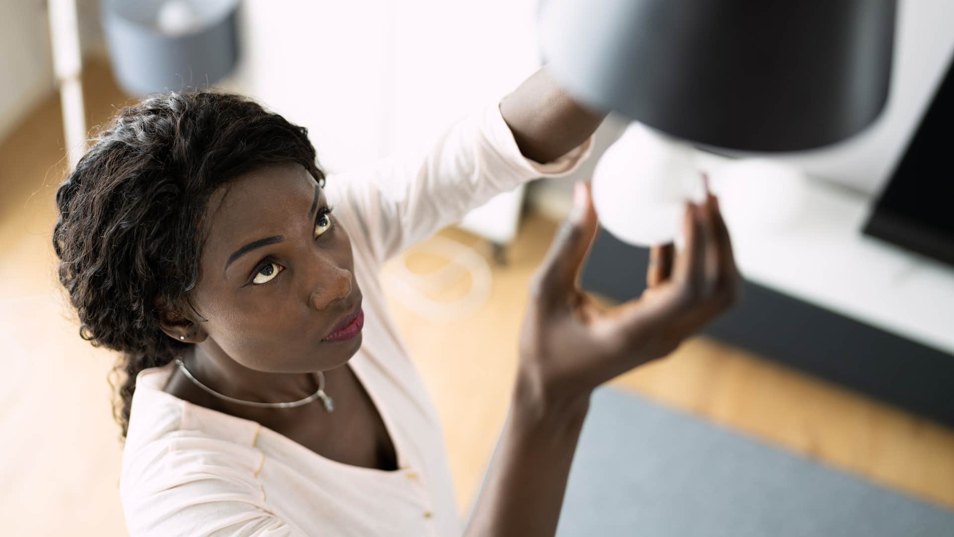 a burned out woman finally changes her old lightbulb in her home