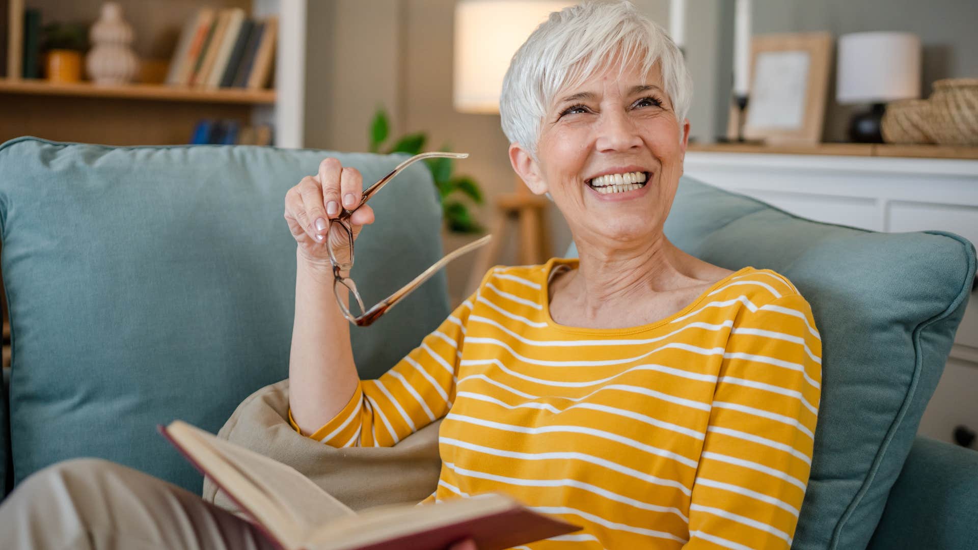 Woman smiling and reading books at home.
