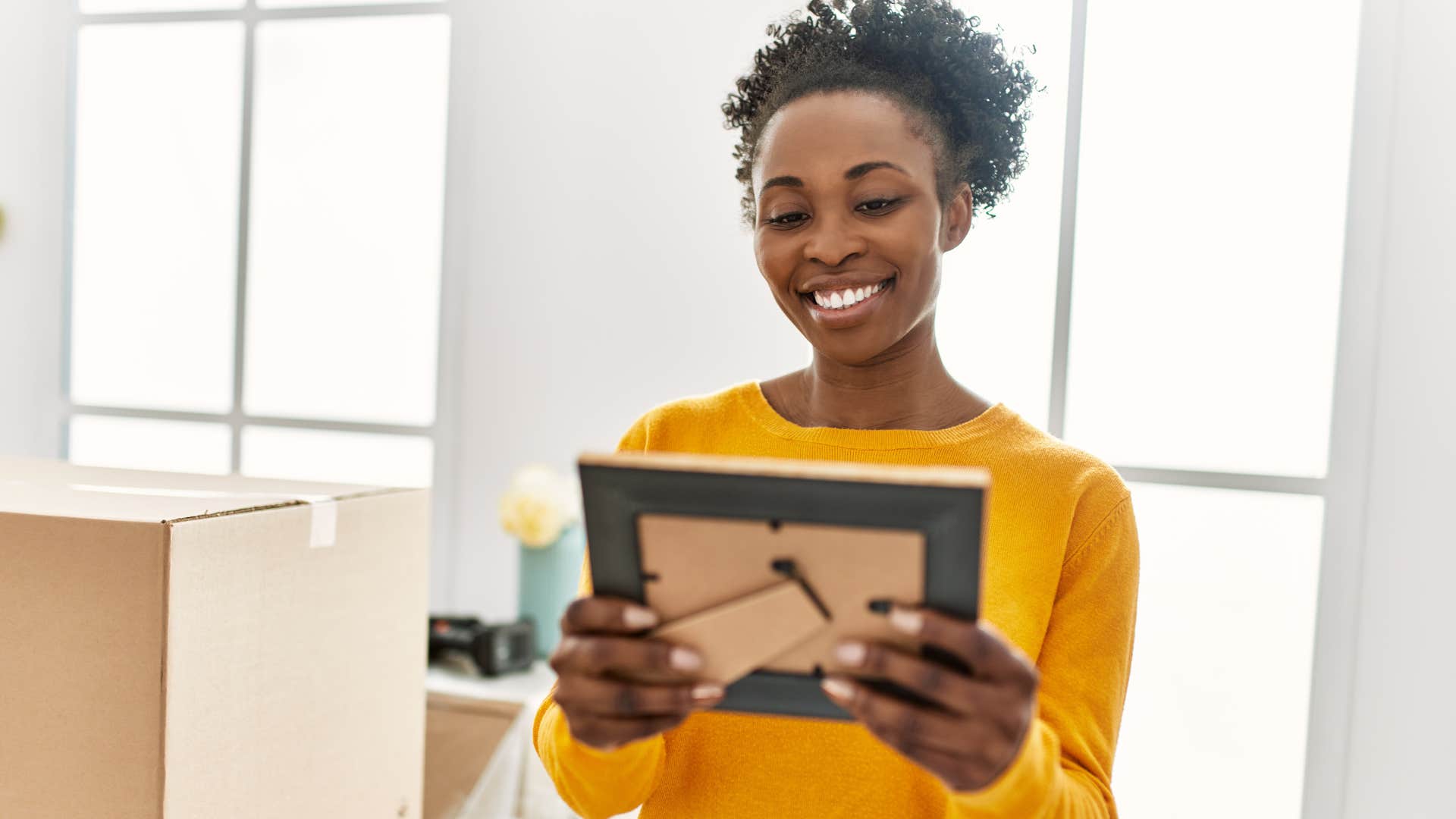 Woman smiling and looking at keepsakes in her home.