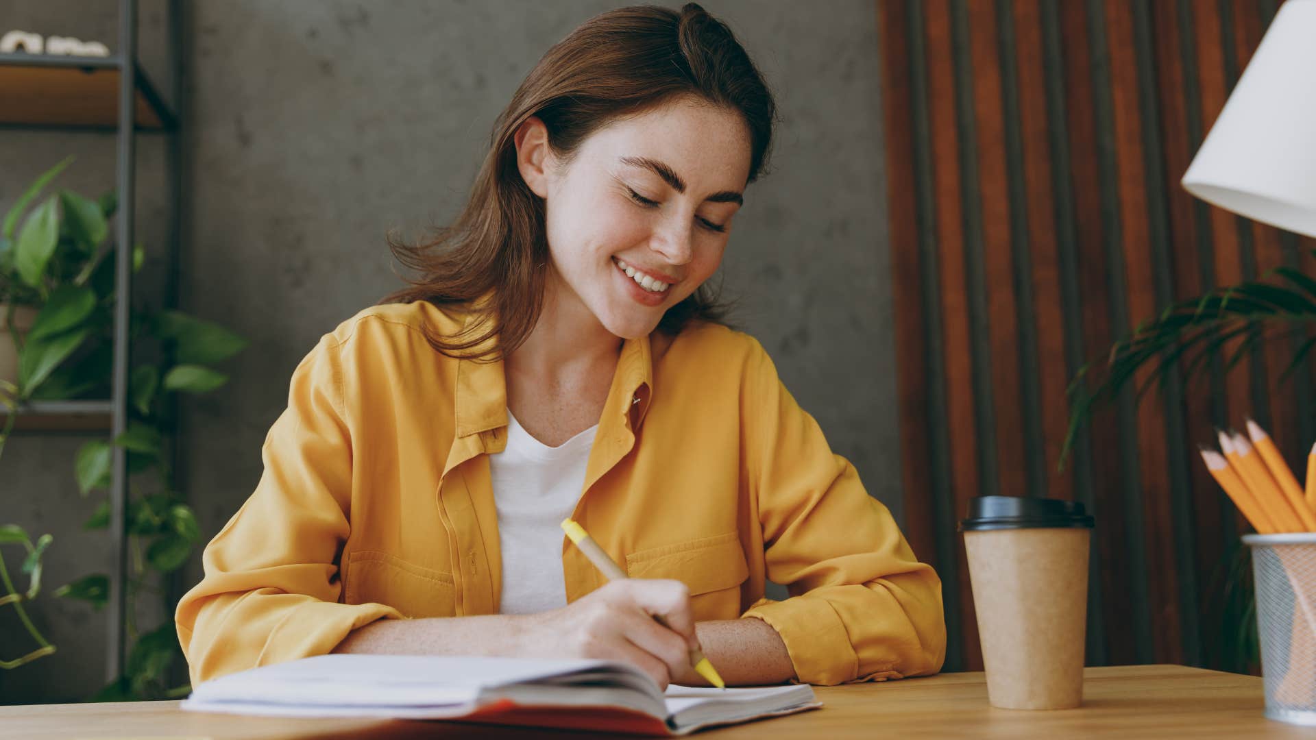 Woman smiling and writing lists at home.
