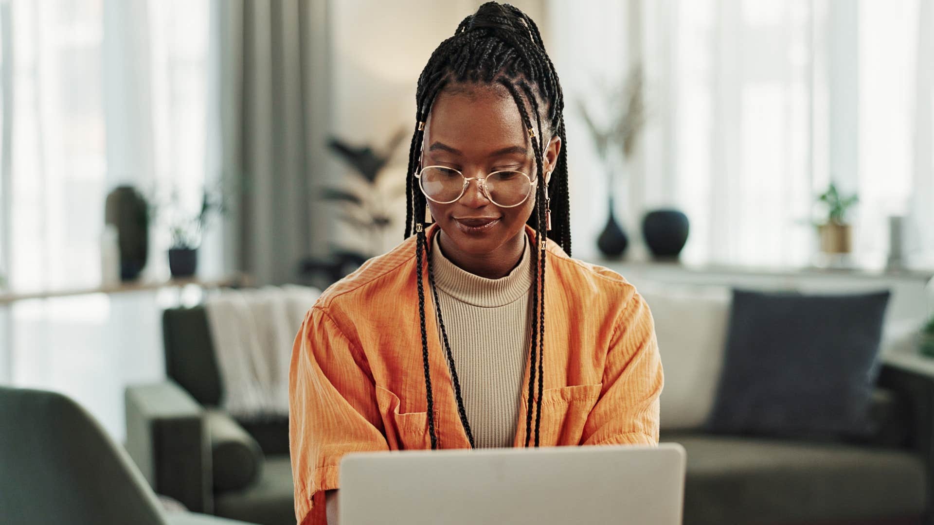 Woman smiling and writing on a planner in her laptop.