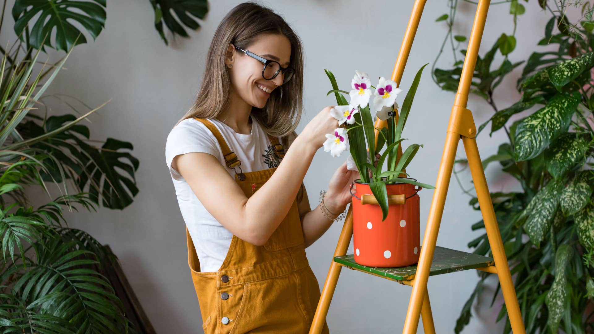 Woman smiling and watering her plants at home.