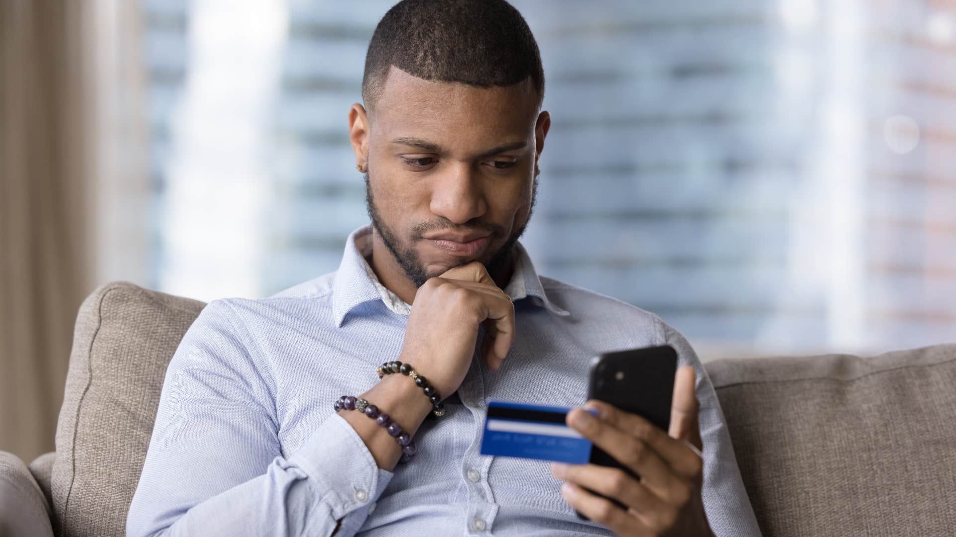 man who doesn't use auto pay looking at his phone and credit card