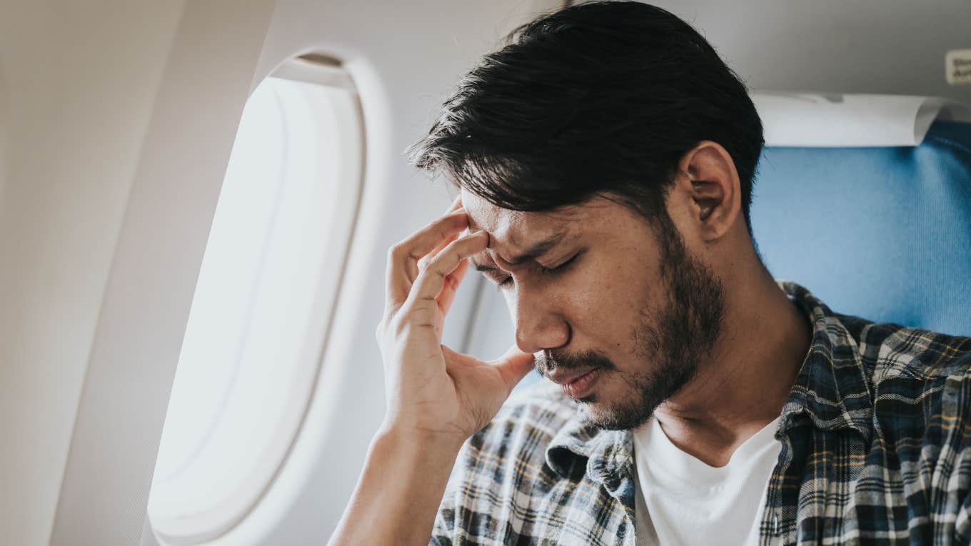 Man looks stressed on plane.