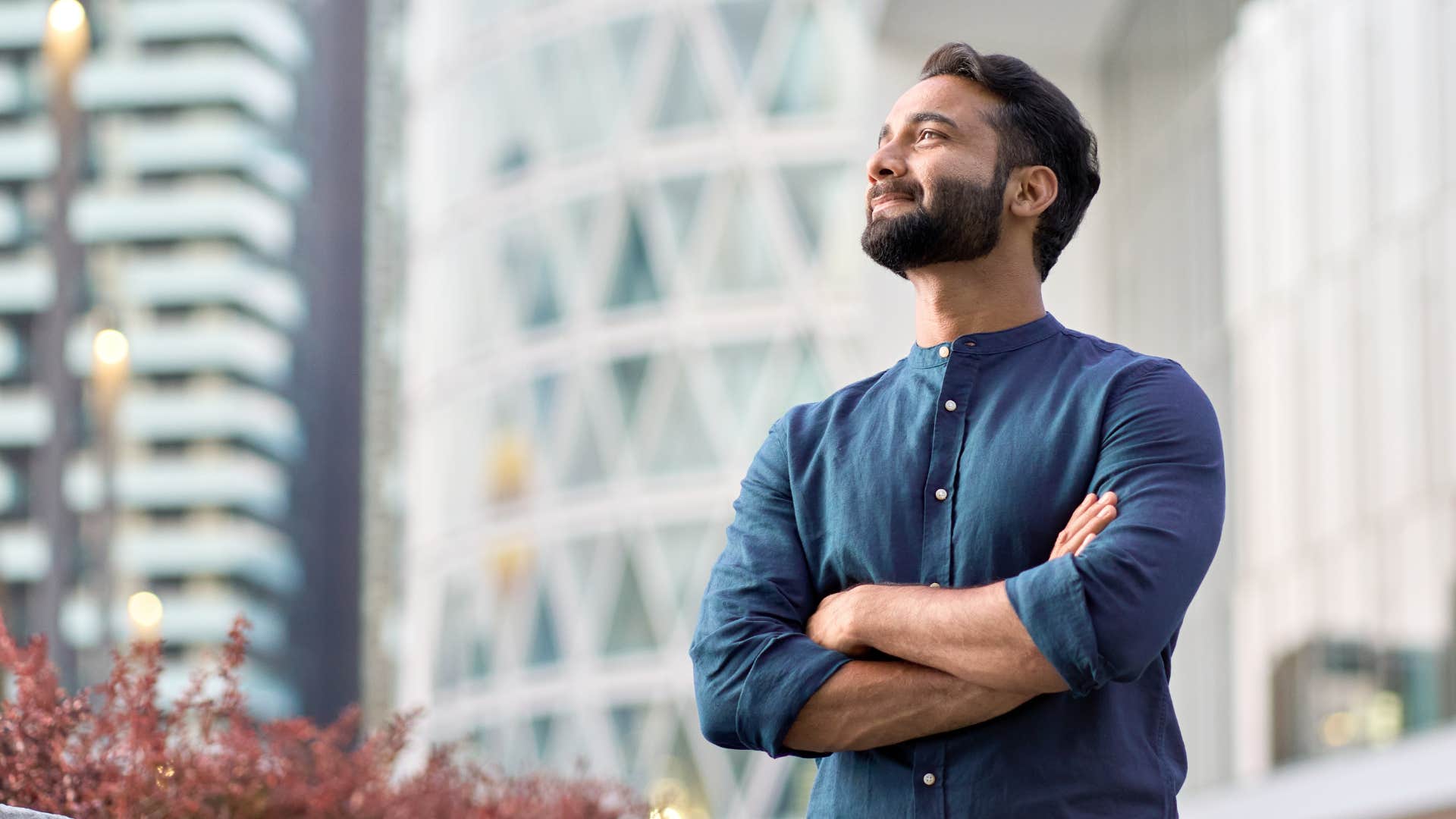 man in blue shirt being hyper individualistic as he crosses arms in confidence