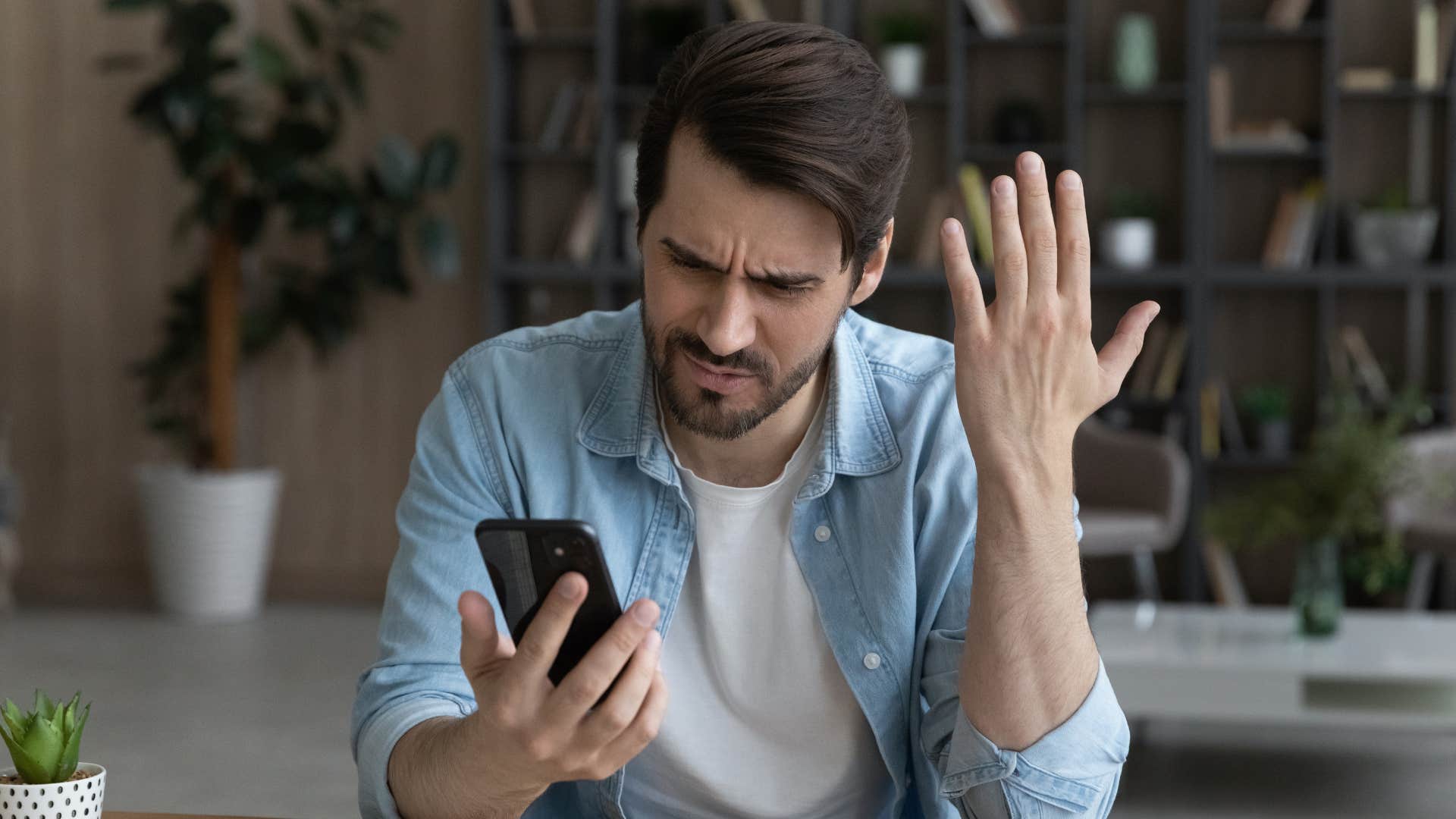 man in blue jacket is tired of the negativity as he stares at phone in confusion