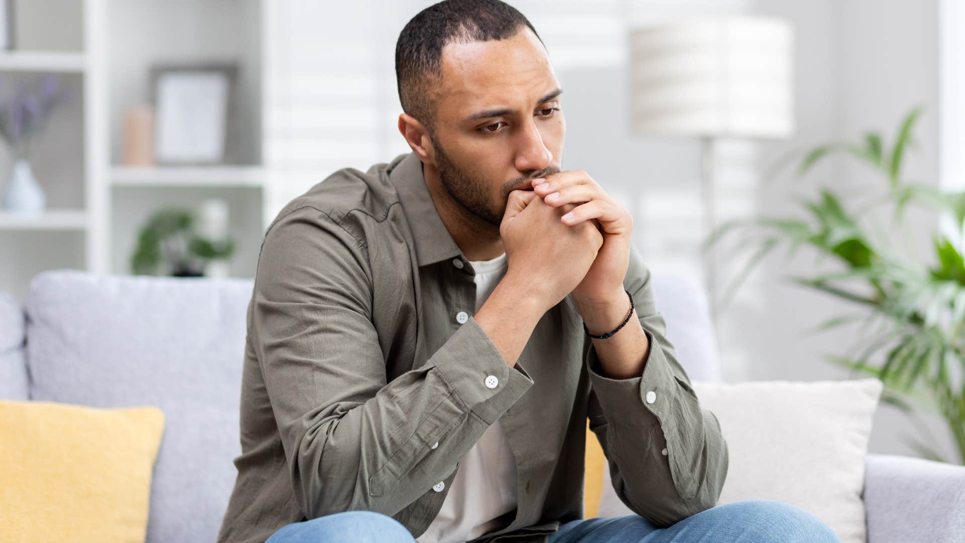 Upset man who doesn't feel heard sitting on his couch.