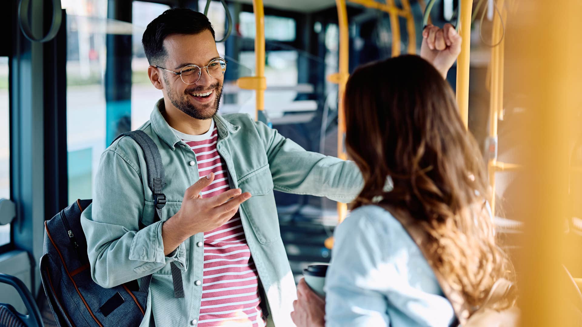 woman talking to man in jean jacket and glasses as he offered seat to someone who needs it more