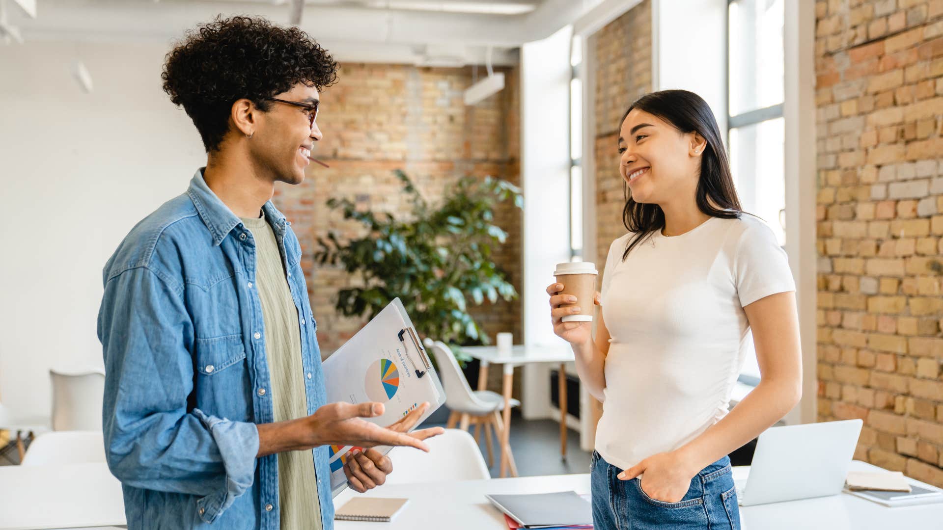 man in blue jean jacket saying please or thank you without thinking to woman in white shirt sipping coffee
