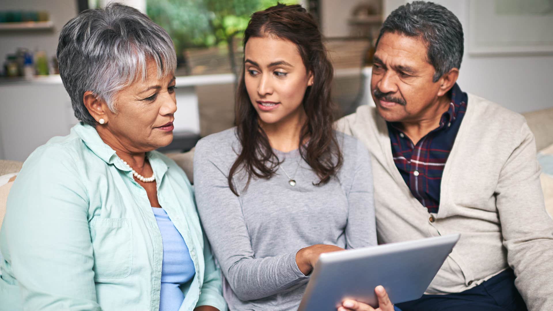 Adult child sitting with her parents who help each other.