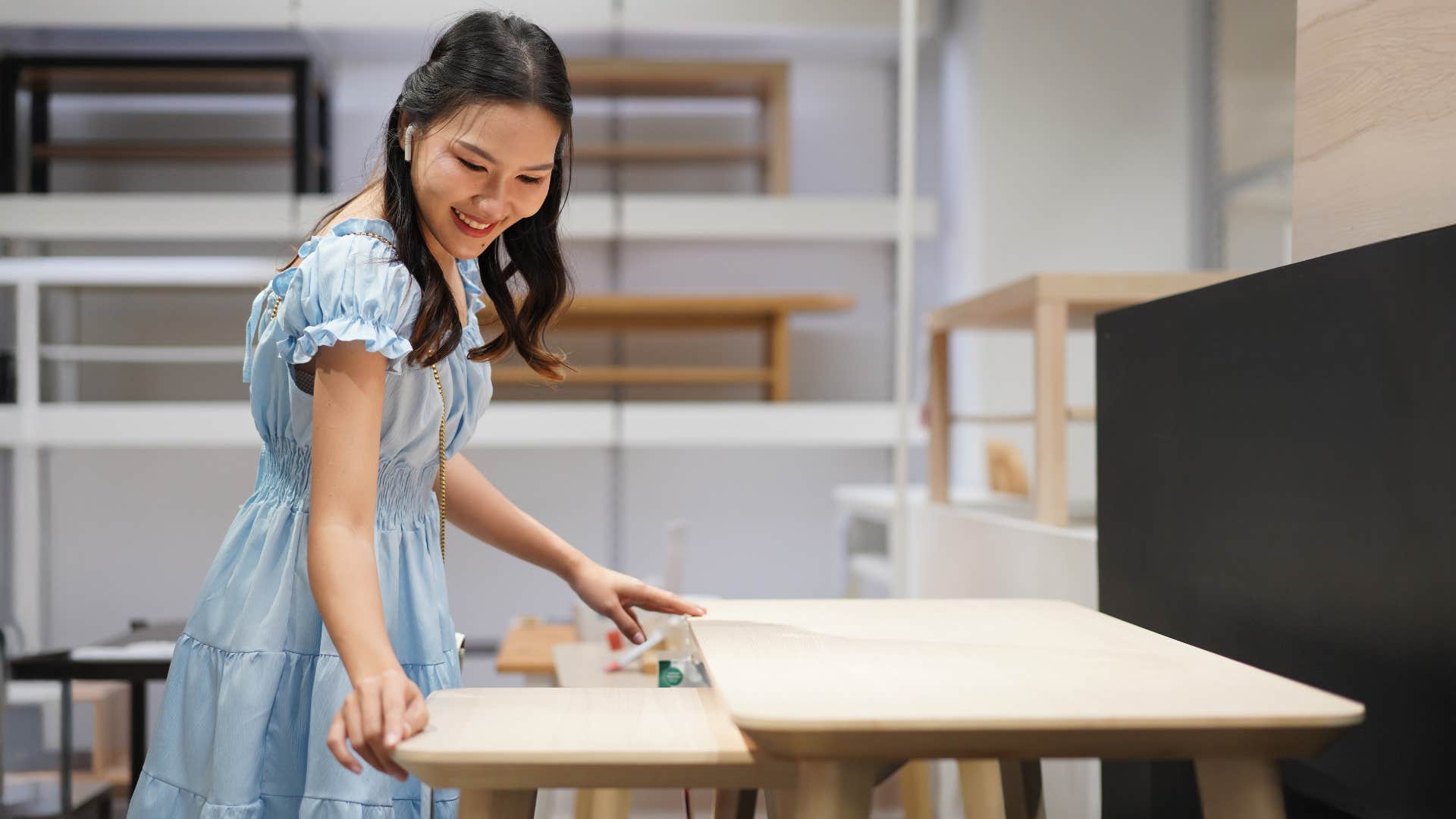 woman in blue dress looking at mismatched furniture as she smiles