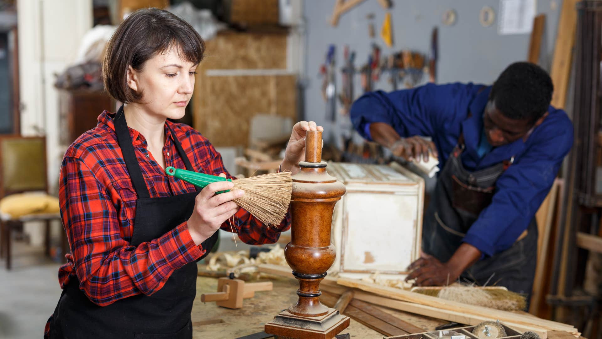 woman in red plaid shirt resurfacing old vintage furniture with man