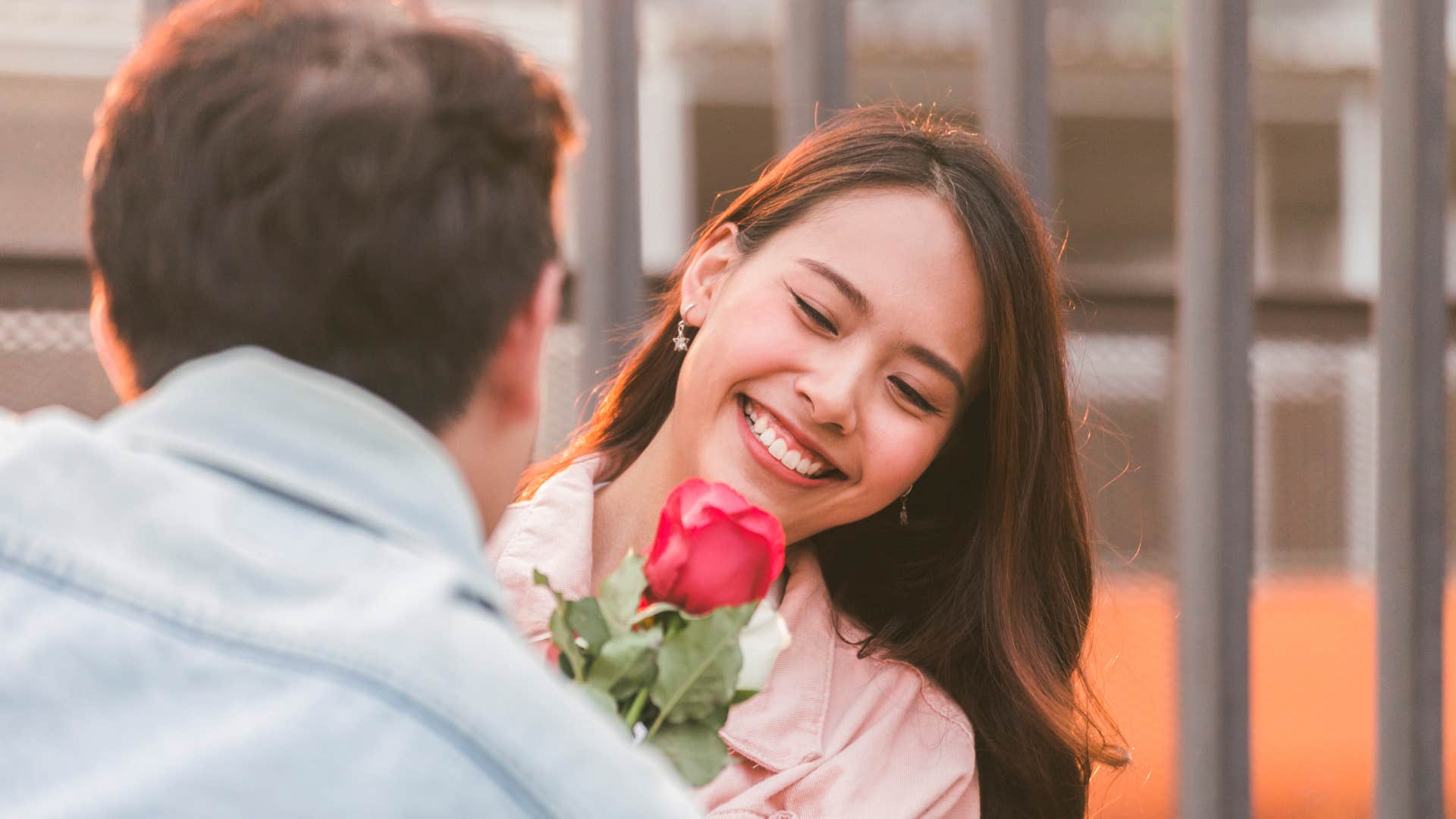 woman with red rose smiling as her standards got higher not lower