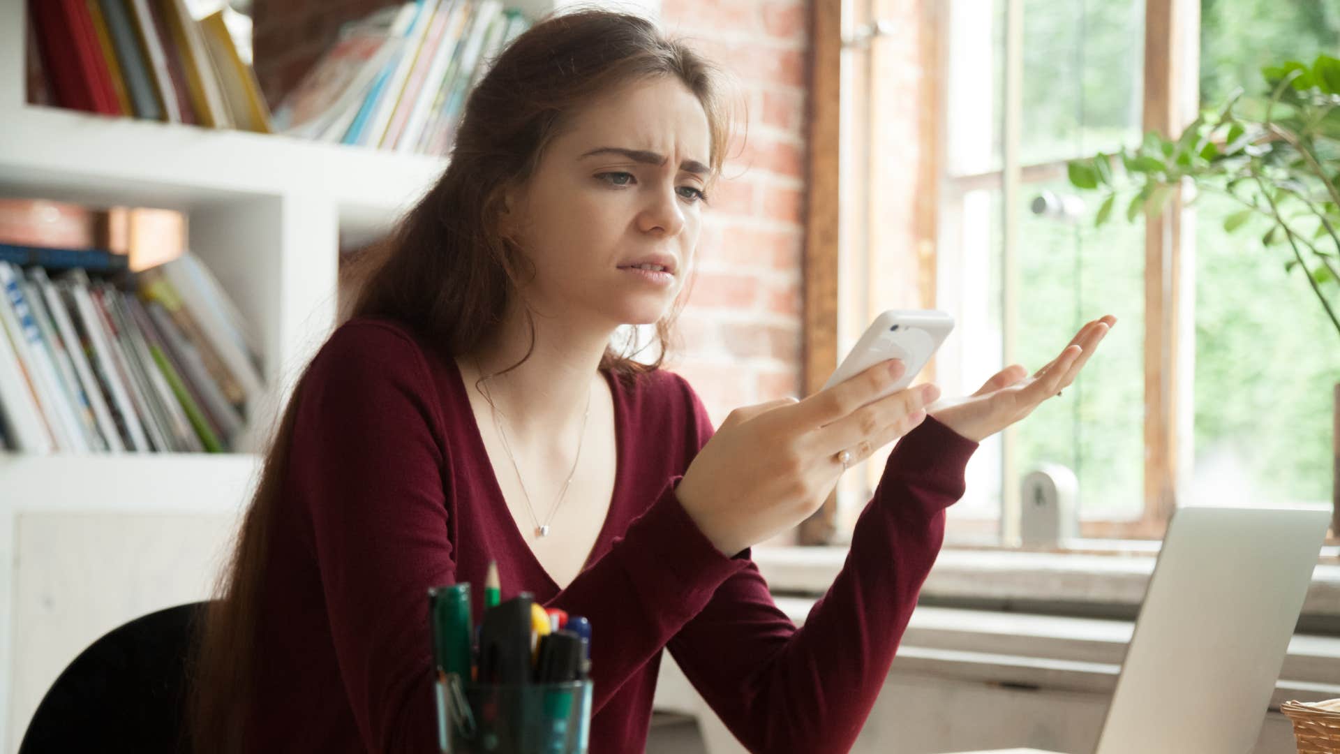 woman in red shirt won't overlook red flags anymore as she looks disgusted at text message