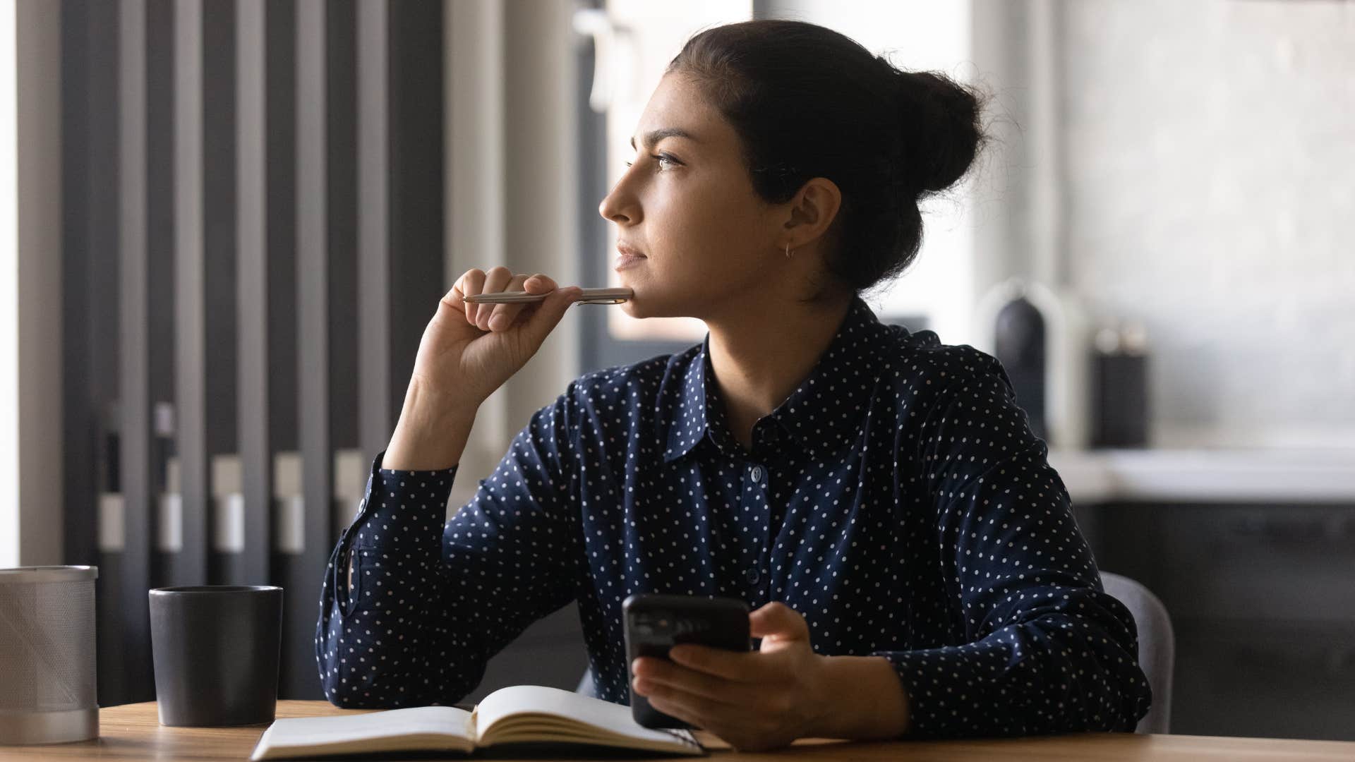 woman in dark blouse thinking of response as she realizes she doesn't need to reply right away