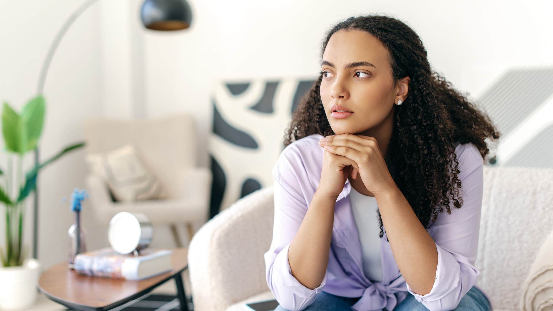 woman in purple shirt sitting down experiencing depression or anxiety as she looks deep in thought