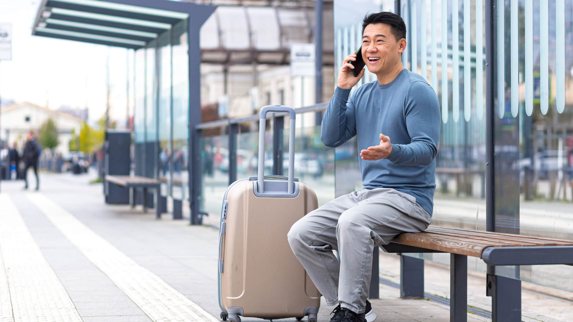 man on bench with suitcase in blue shirt lacking transportation