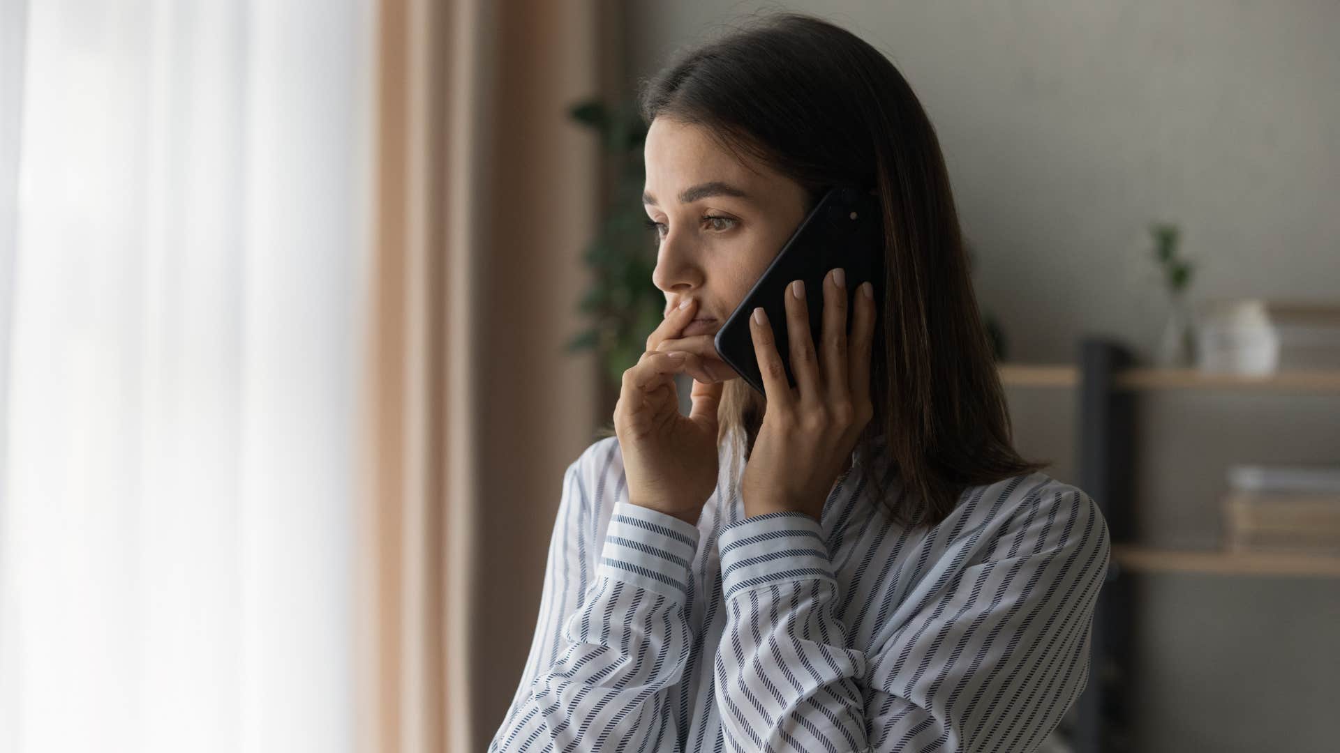 woman in stripped shirt loosing touch with her old friends as she calls someone on the phone