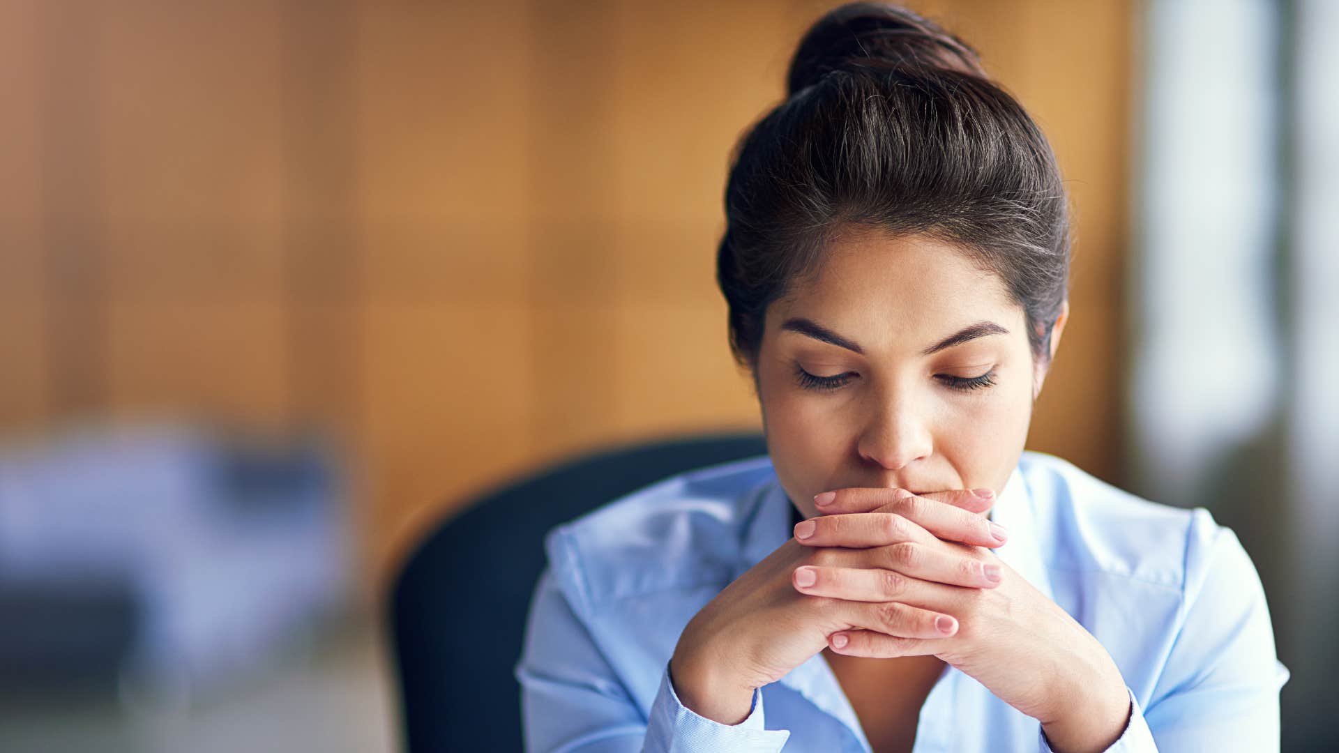 woman in blue shirt is no longer interested in faking it as she closes eyes and thinks heavily