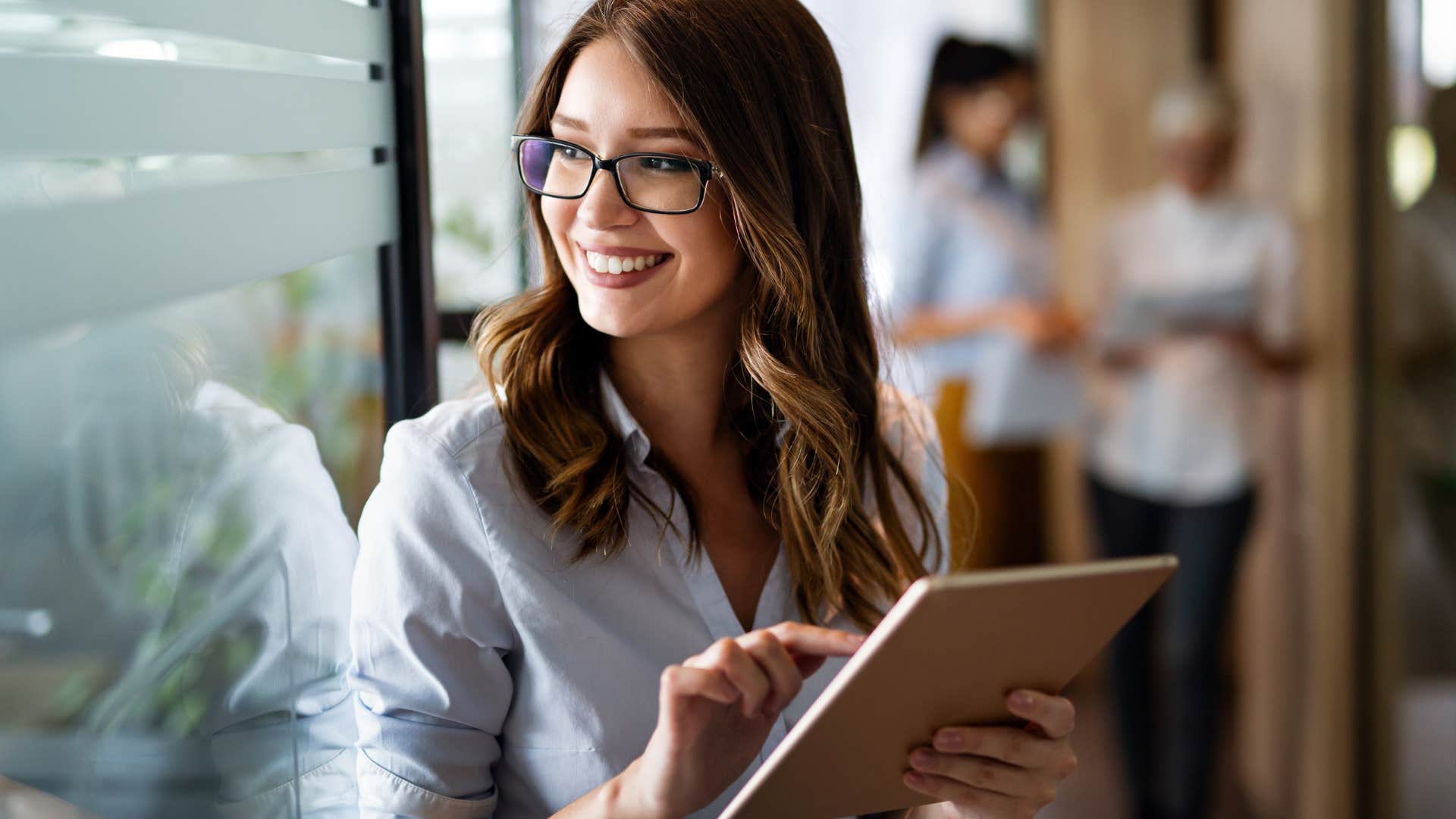 businesswoman smiling in office while holding tablet