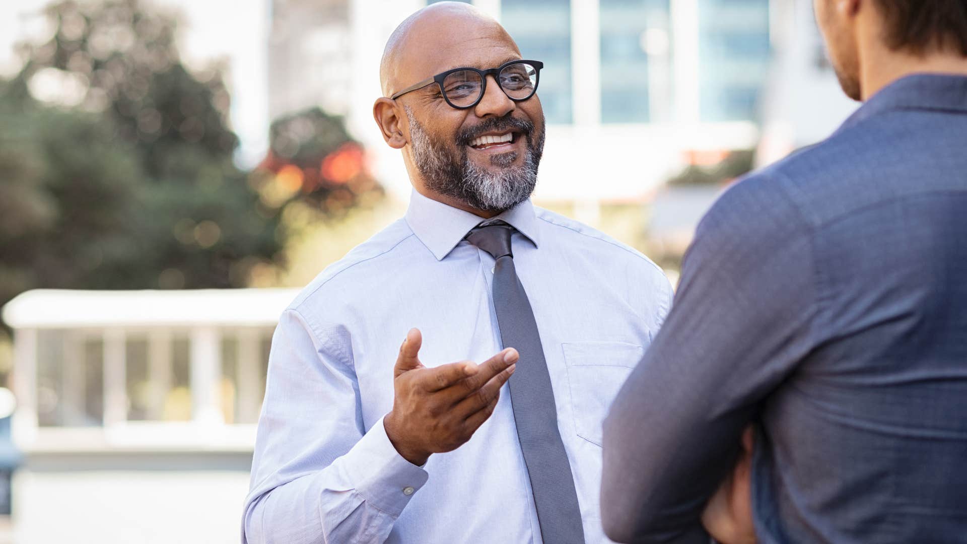 Man who doesn't compete with others talking to a co-worker.