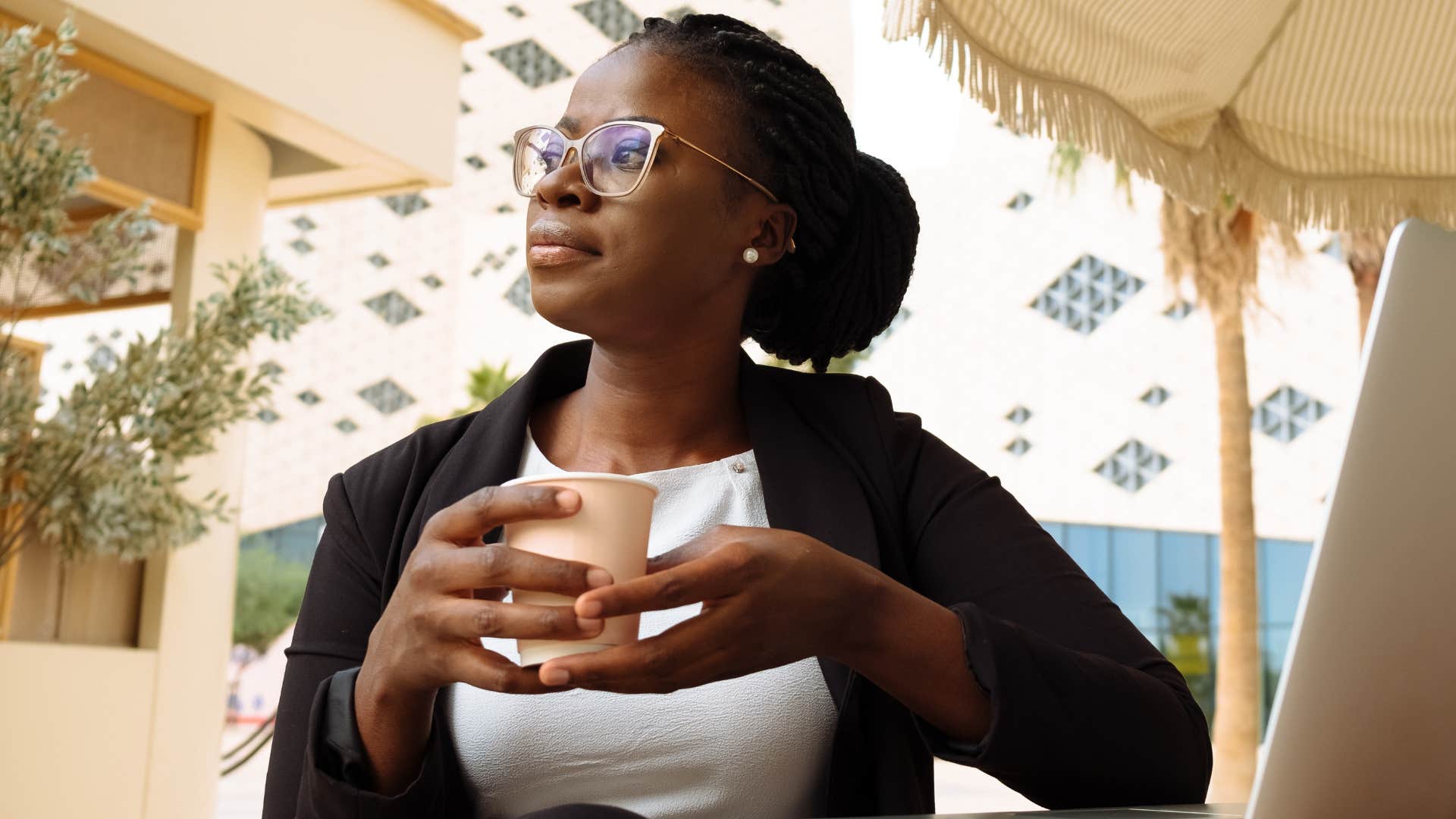 Woman who's sick of being disappointed sitting outside with a coffee.