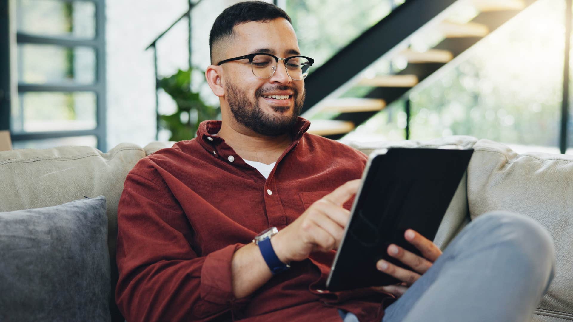 Man who's not chasing validation sitting at home scrolling on a tablet.