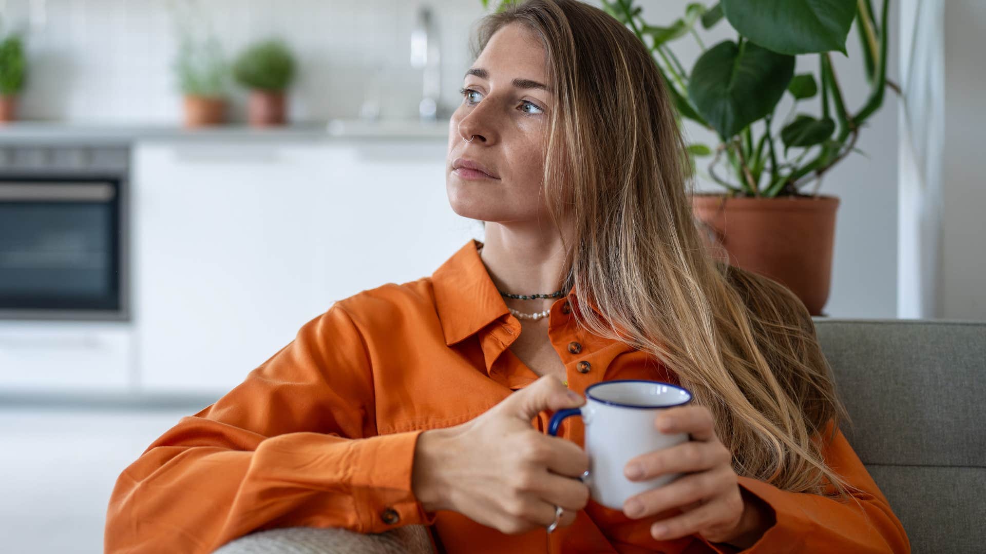 Introspective woman looking out her window at home.