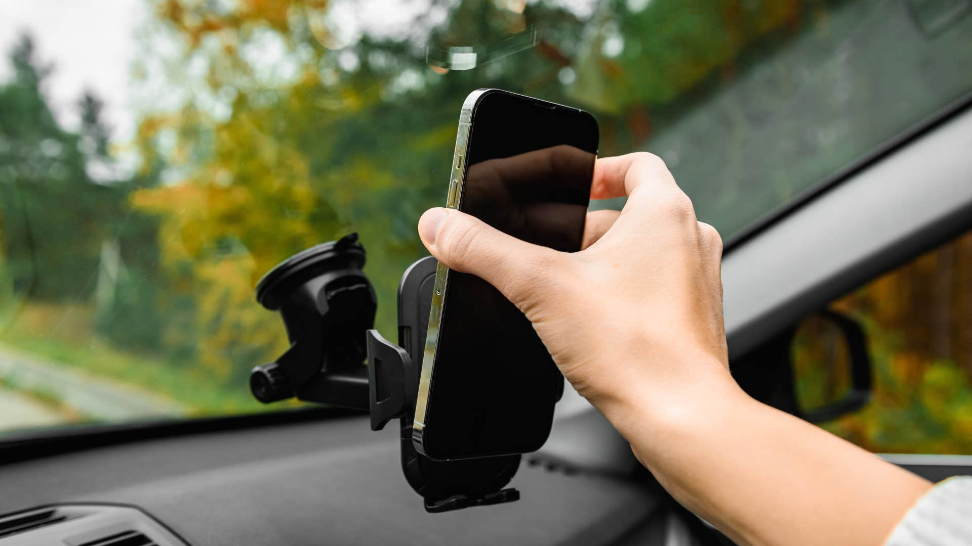 a high iq woman places her phone on a mount into of her dashboard