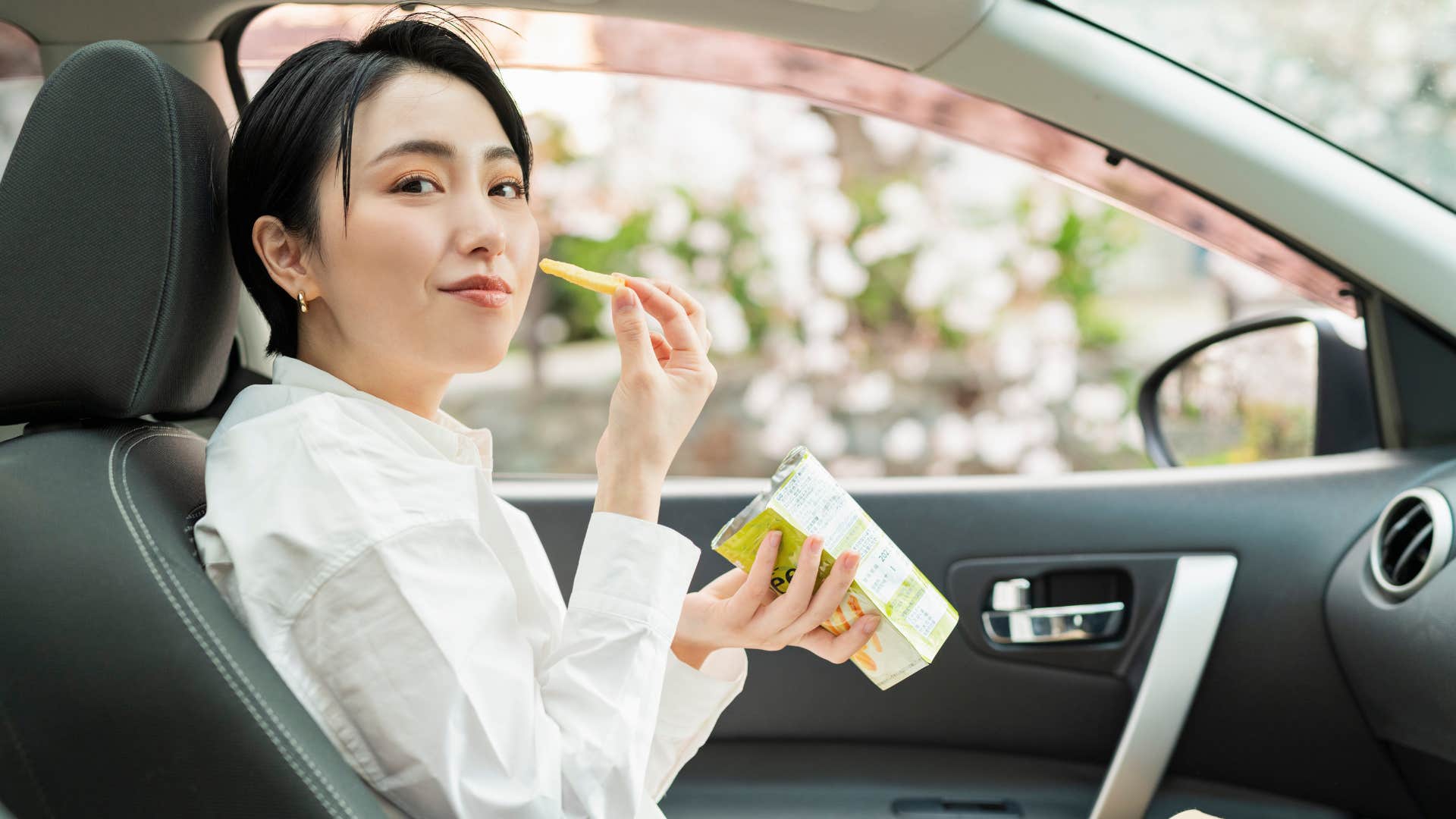 a high iq woman enjoys a snack while in her vehicle