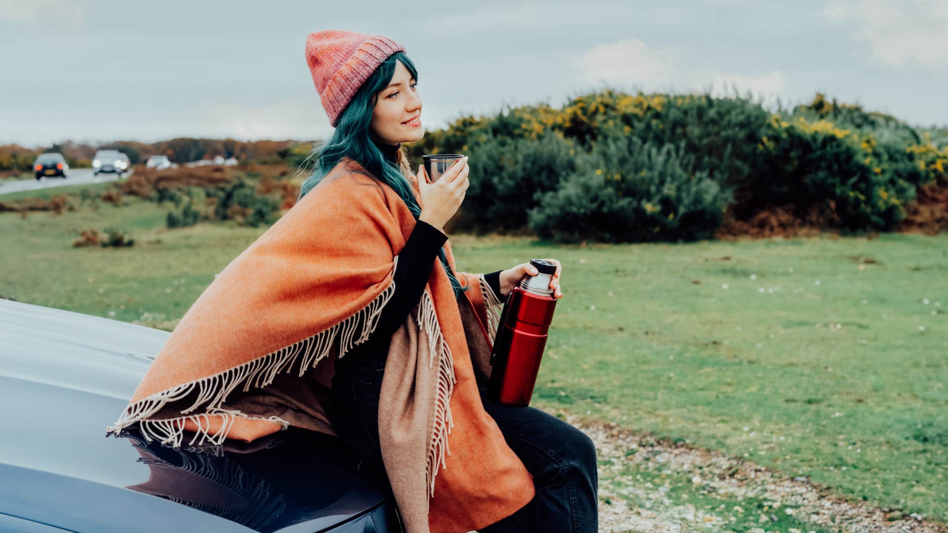 a high iq woman uses the poncho she had in her trunk as the weather changed
