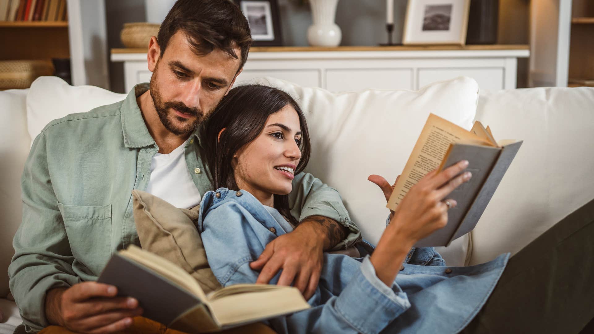 Happy couple reading books together on their couch.