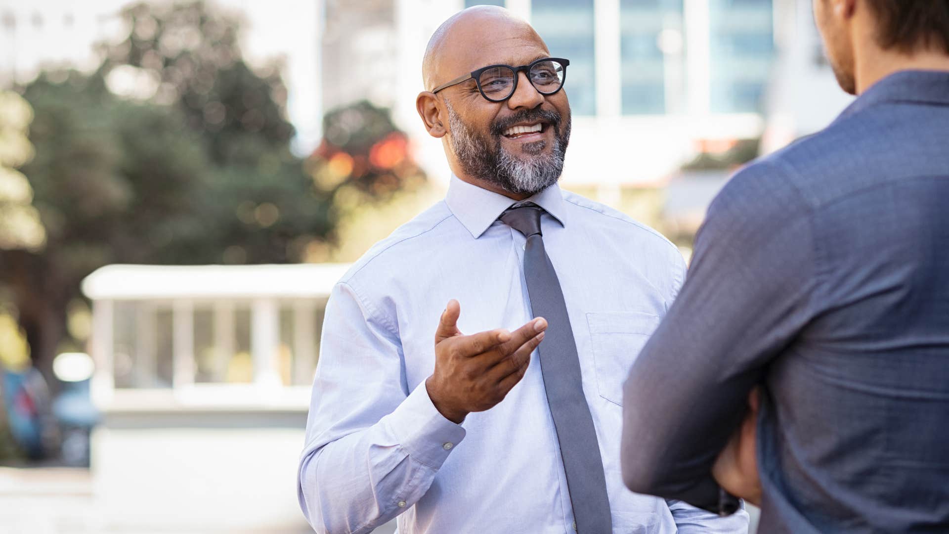 man smiling and saying good question let me get back to you to colleague at work