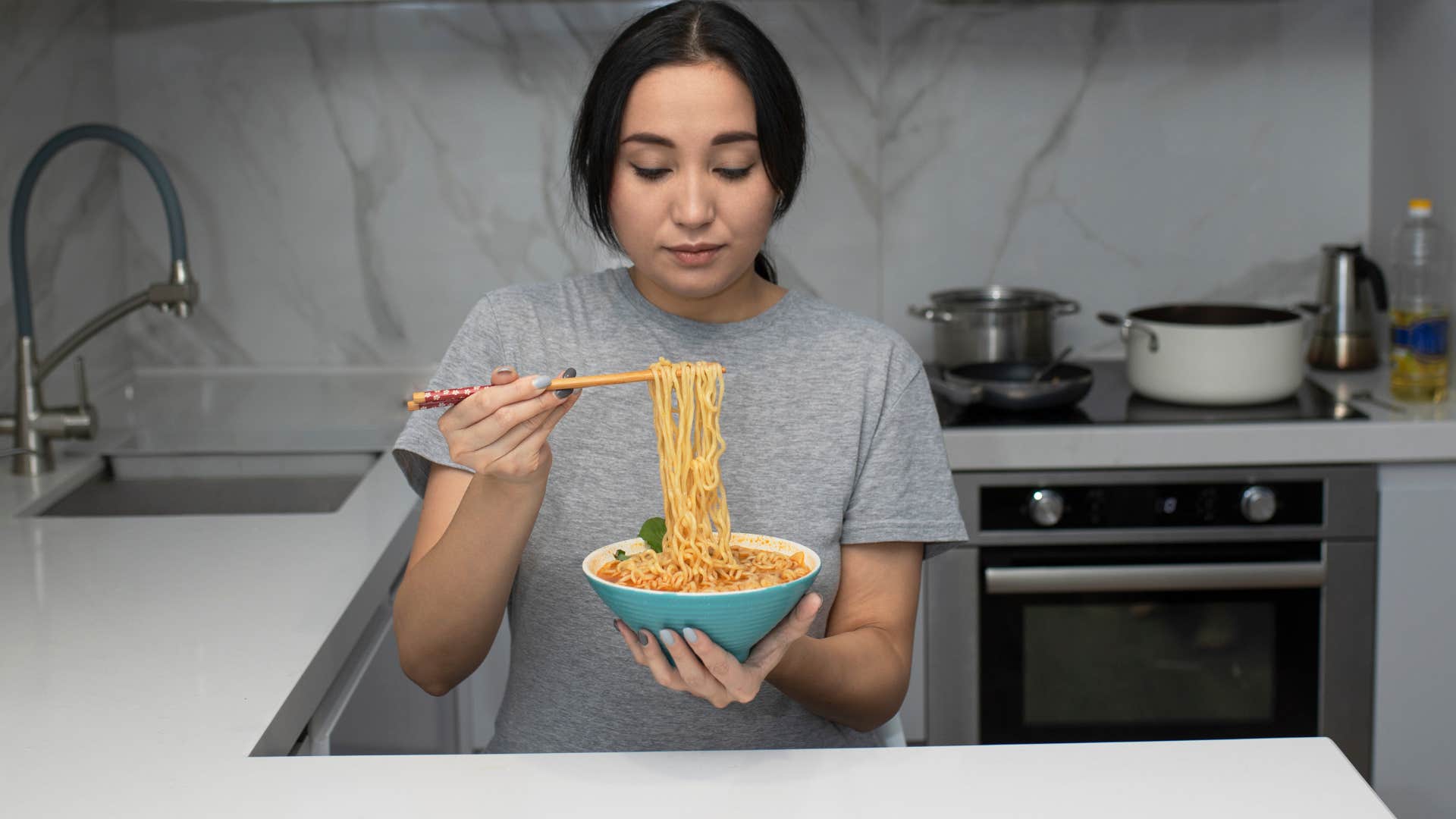 woman eating ramen noodles after cooking at home