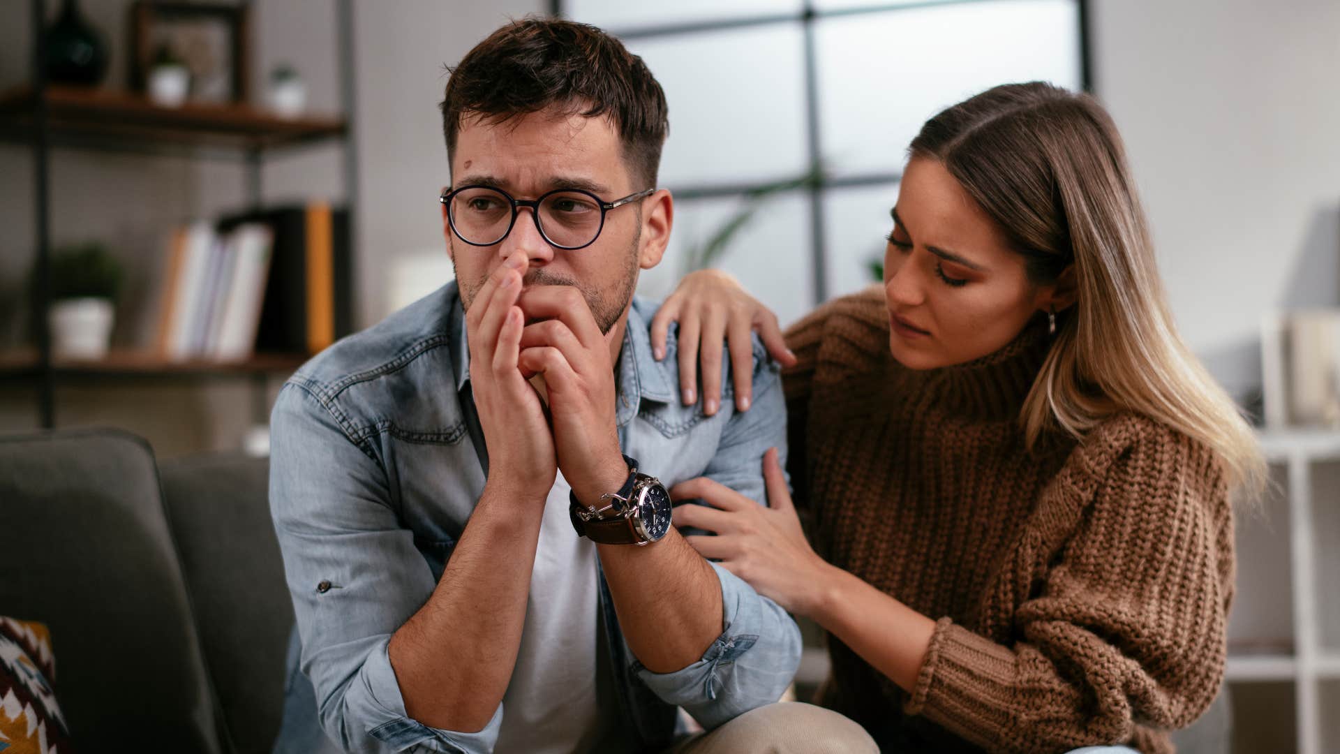 man looking visibly upset but faking nonchalance as he says don't worry about me while woman comforts him 