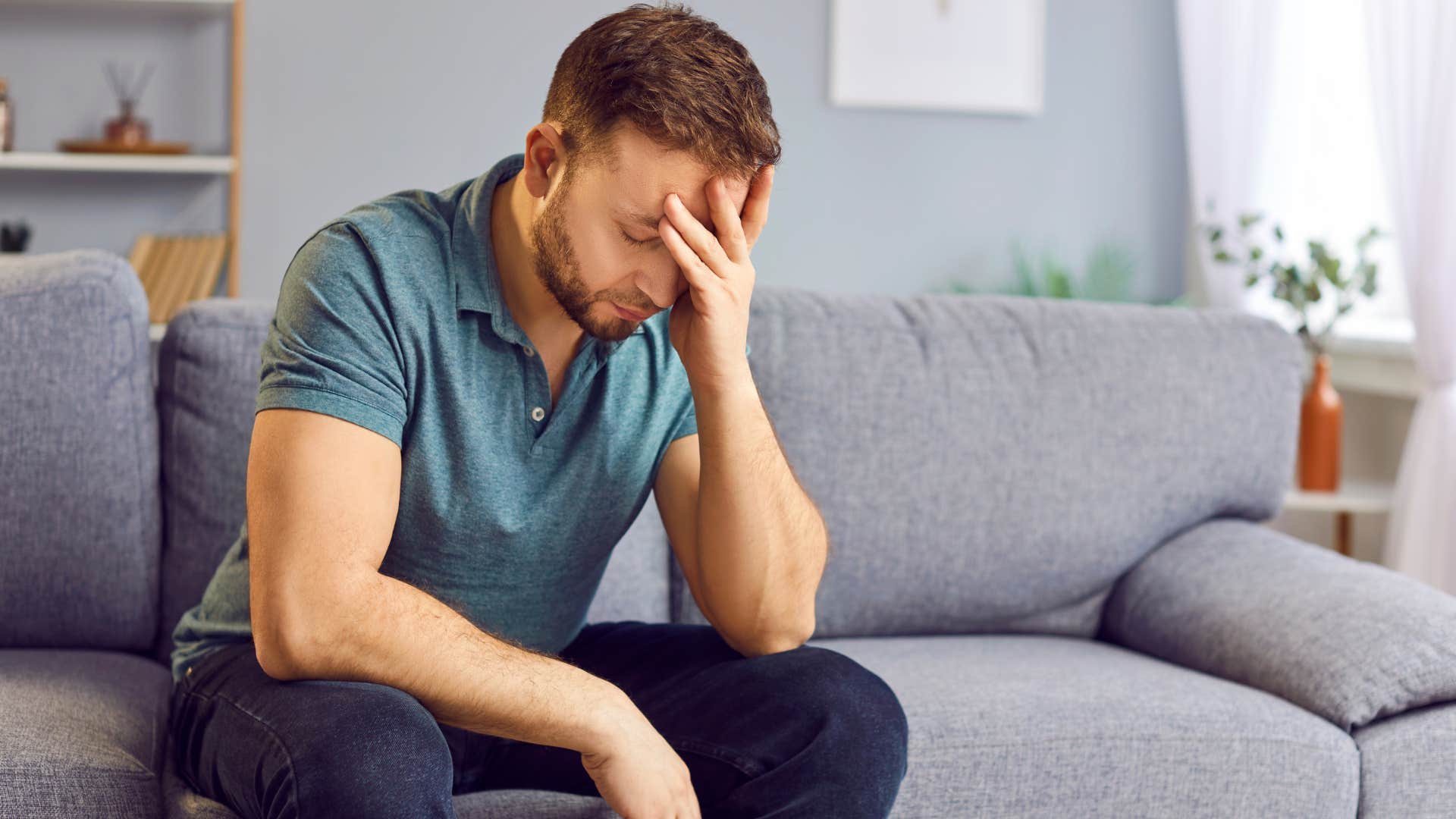 man clearly upset on gray couch as he thinks i feel like a stranger in my own house