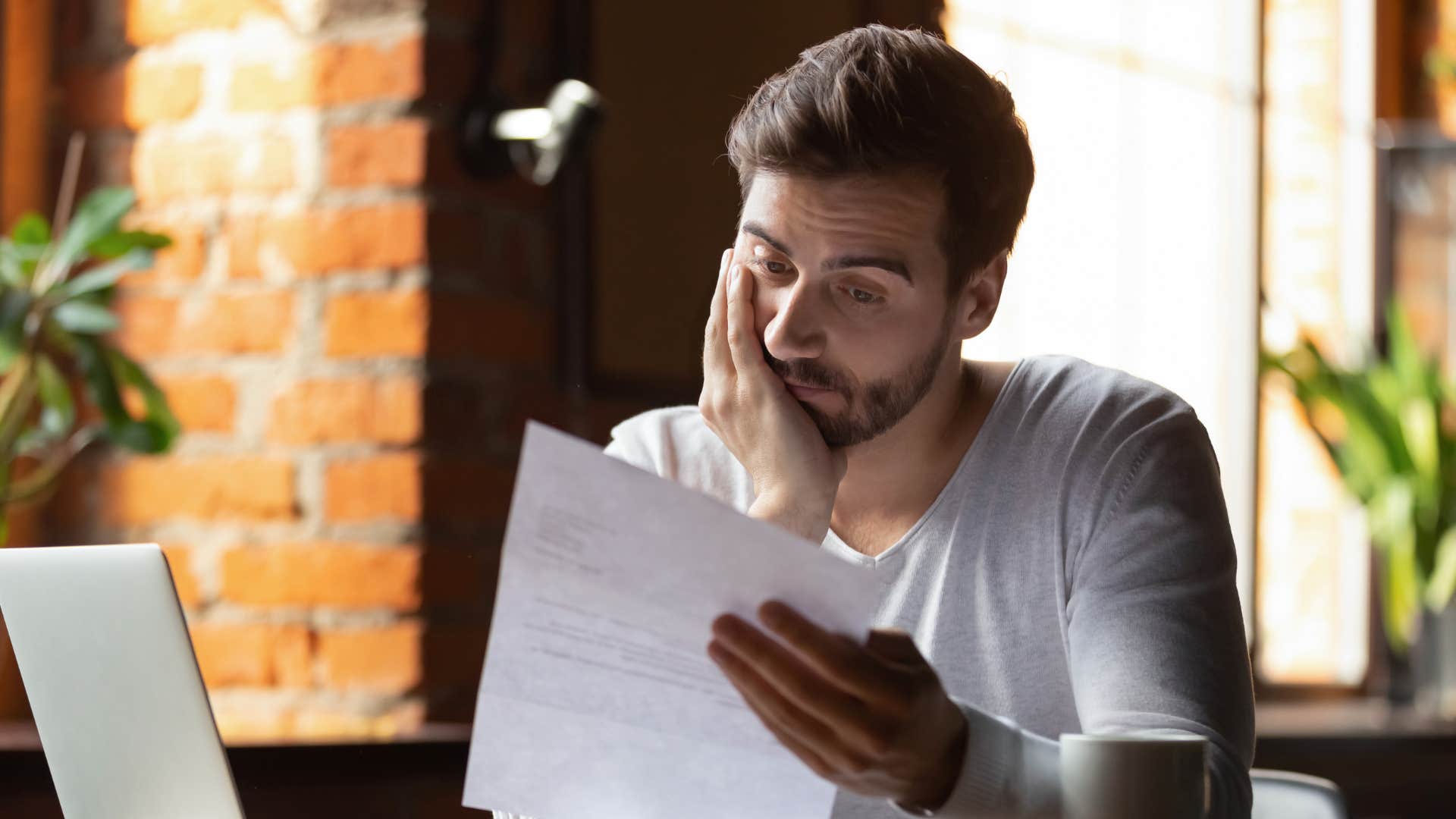 man in white shirt holding up paper and thinking i'm just here to pay the bills