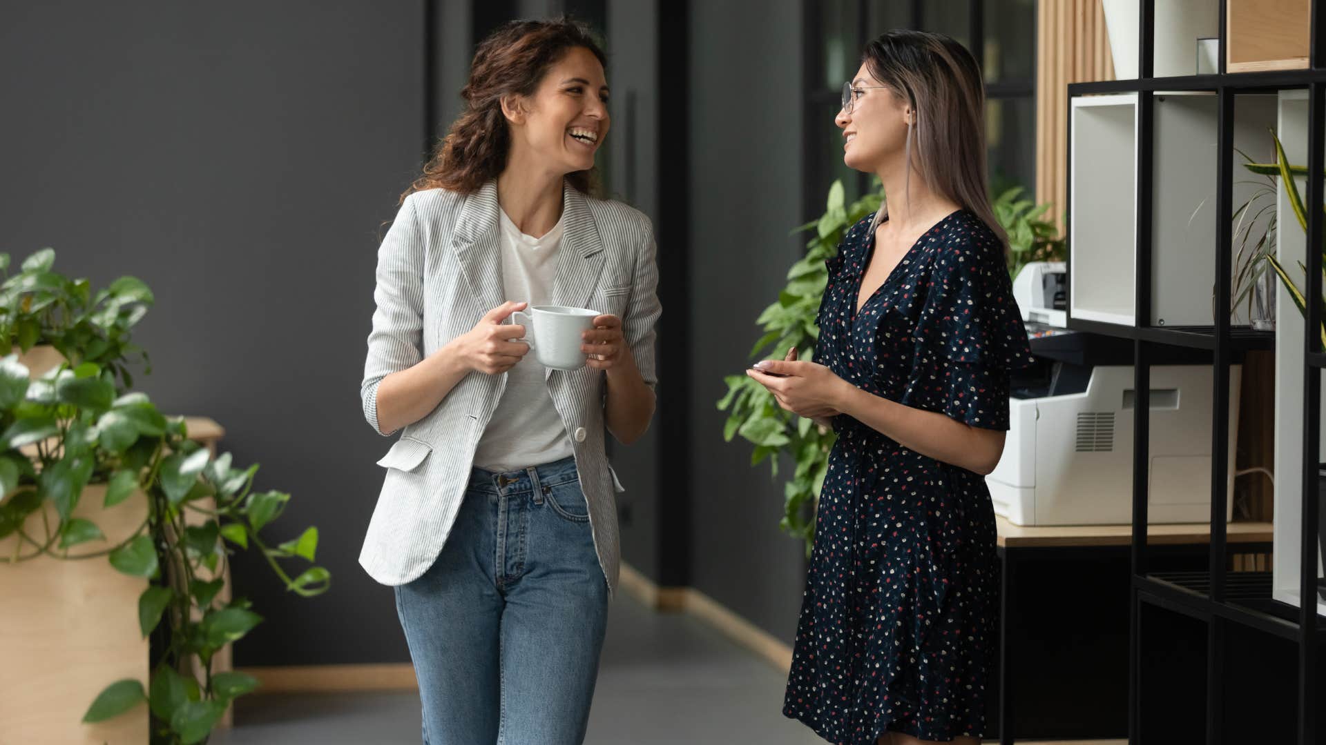 woman in white shirt saying i'm managing as she passes coworker in black dress