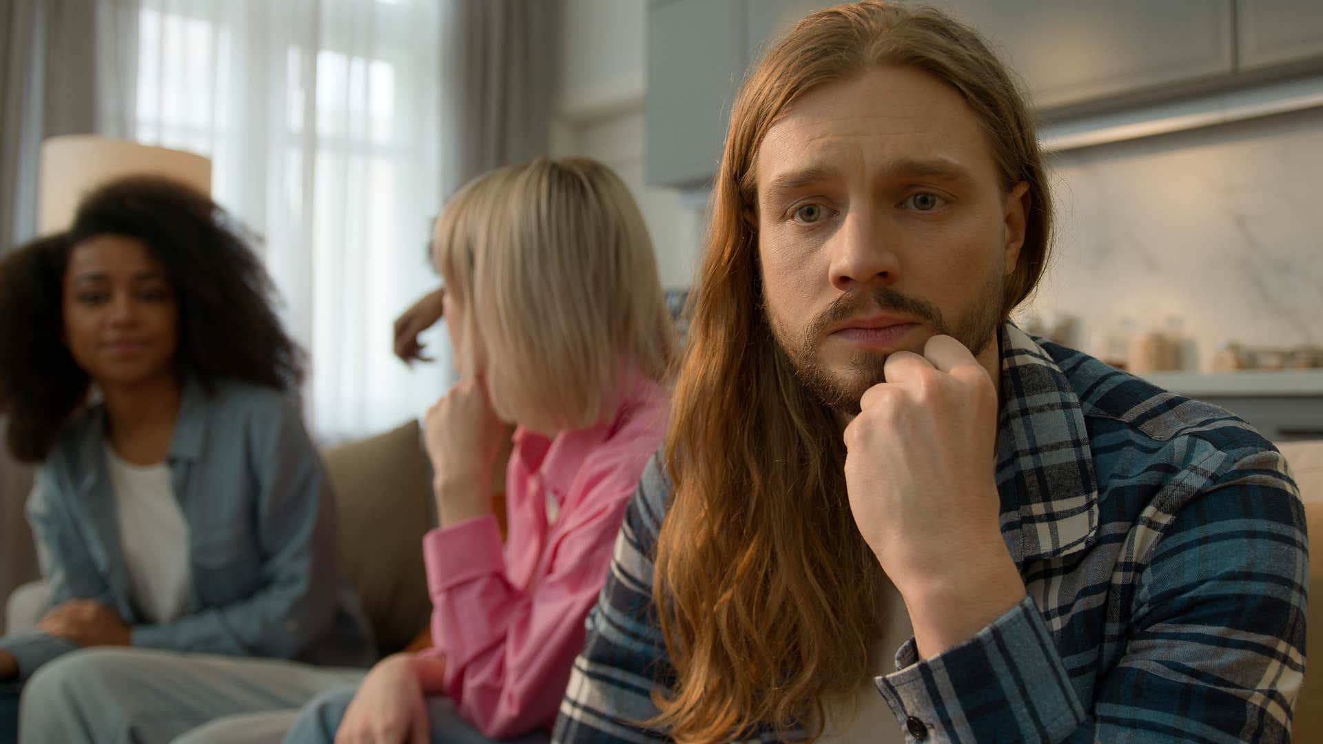 miserable man thinking it doesn't matter while turned away from his friends