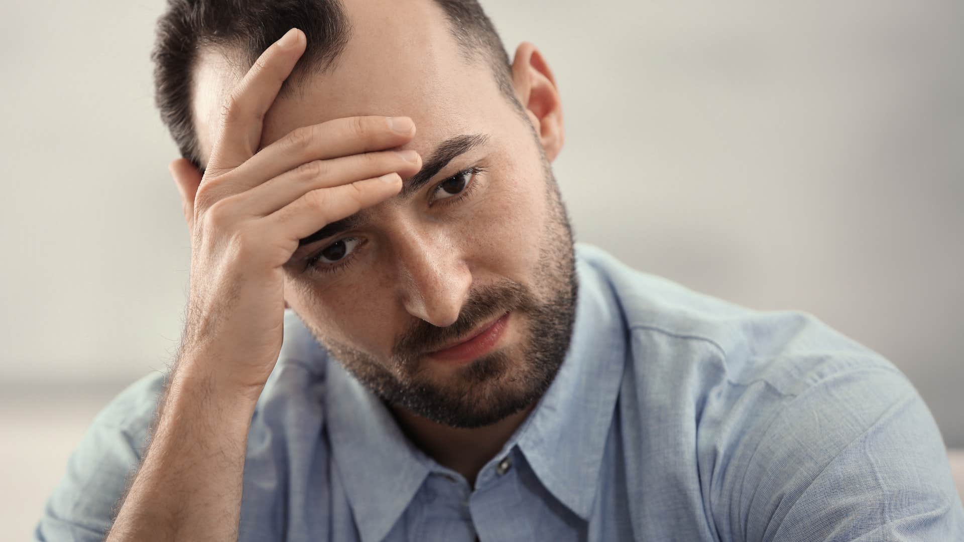miserable man holding his head and saying whatever