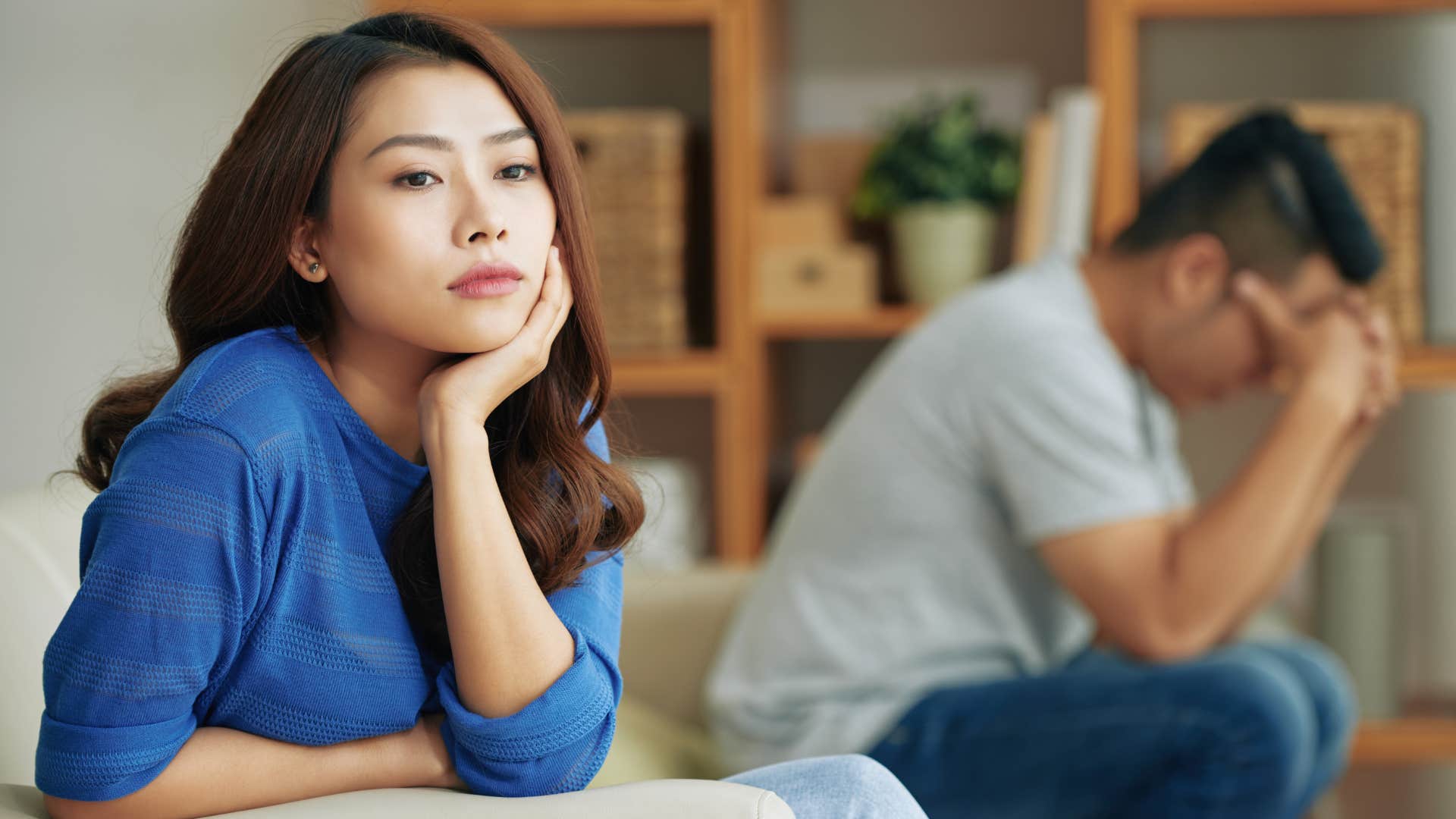 woman in blue shirt thinking i feel so alone when i'm with you as man is in deep thought 