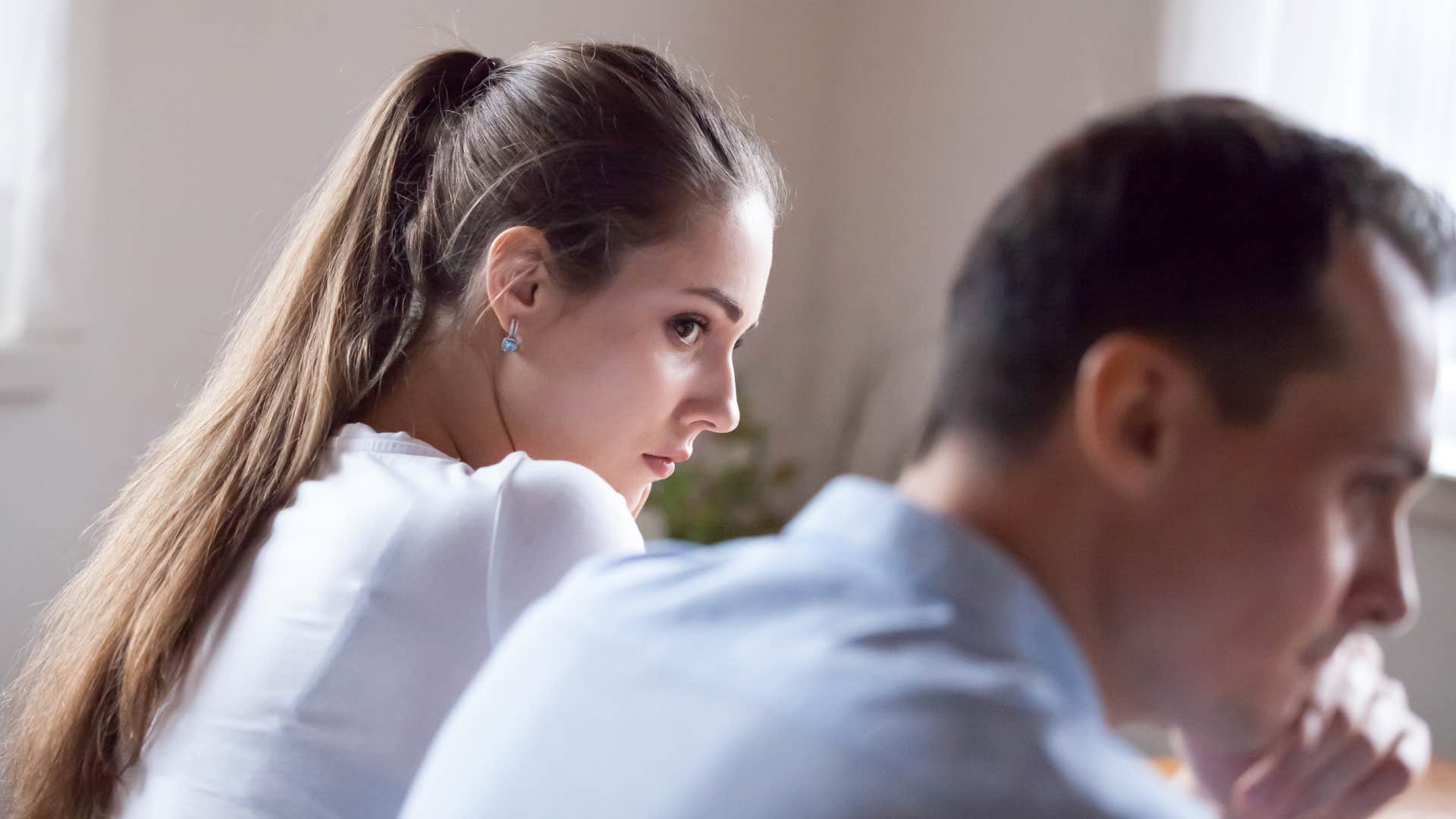 woman in white shirt looking at man in blue shirt thinking things feel off lately