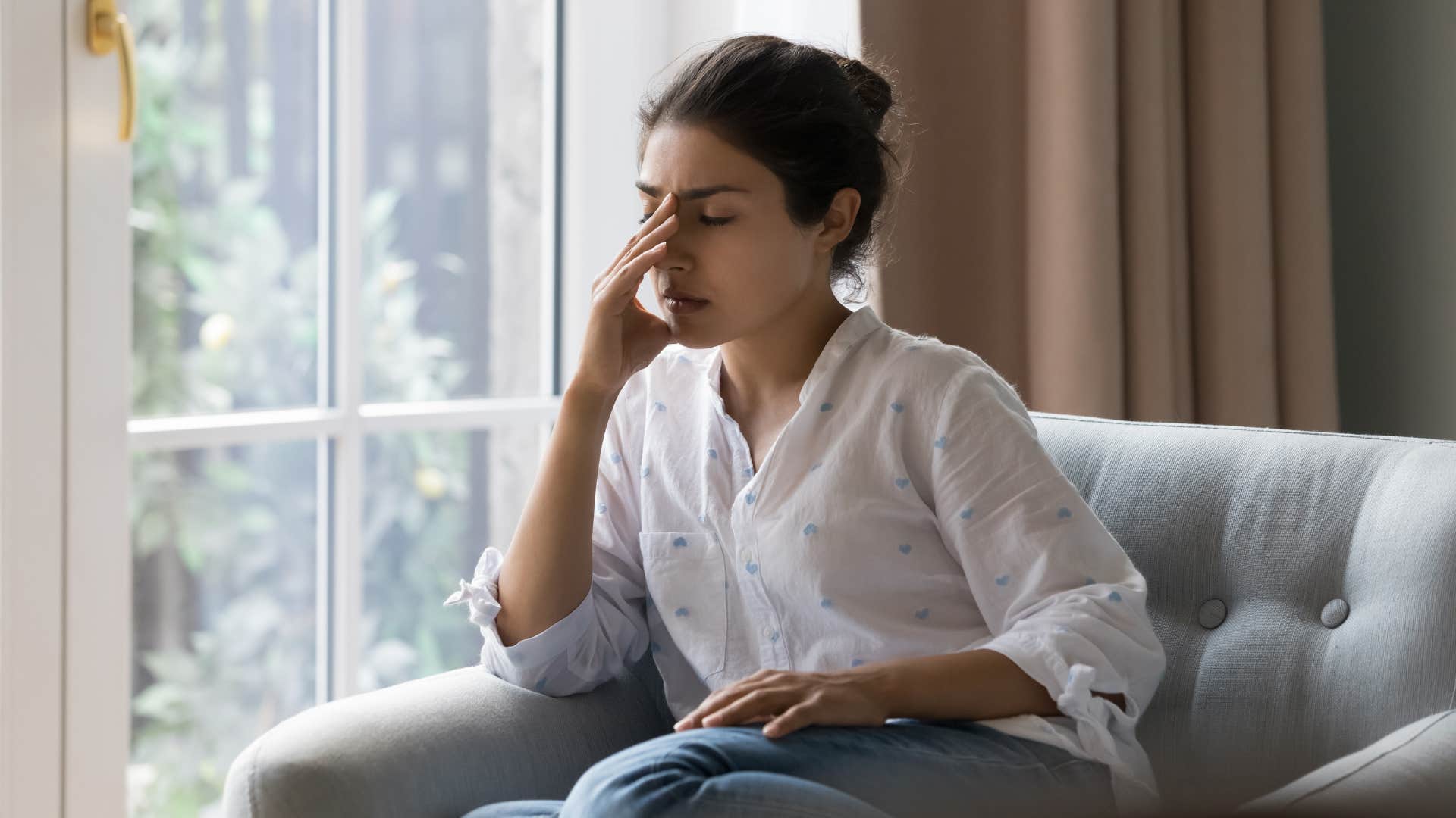 woman in white shirt sitting down thinking i'm tired