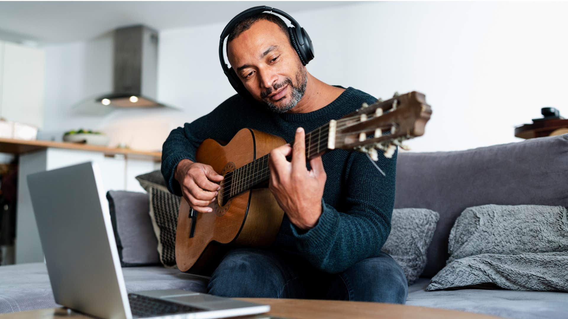 man being a cultural cultivator as he records himself playing guitar with headphones