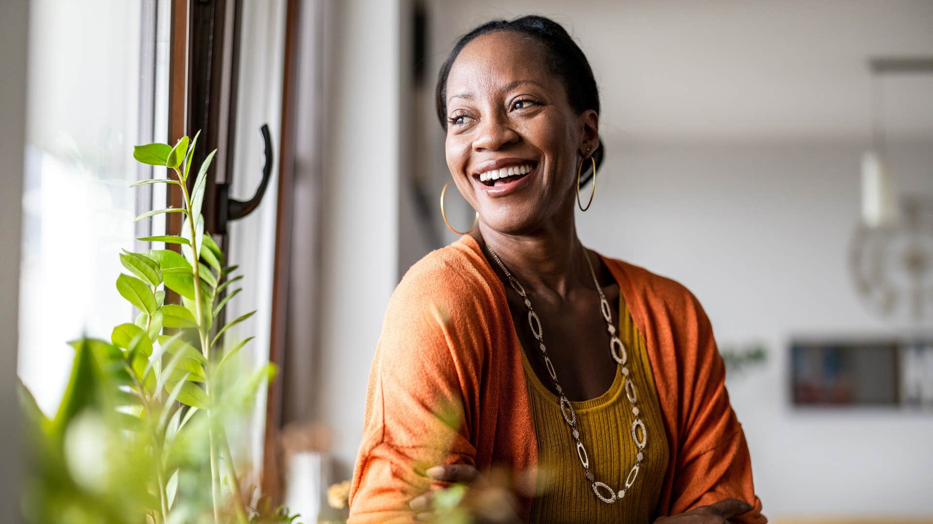 woman having a strong appreciation for simplicity as she looks out the window and smiles